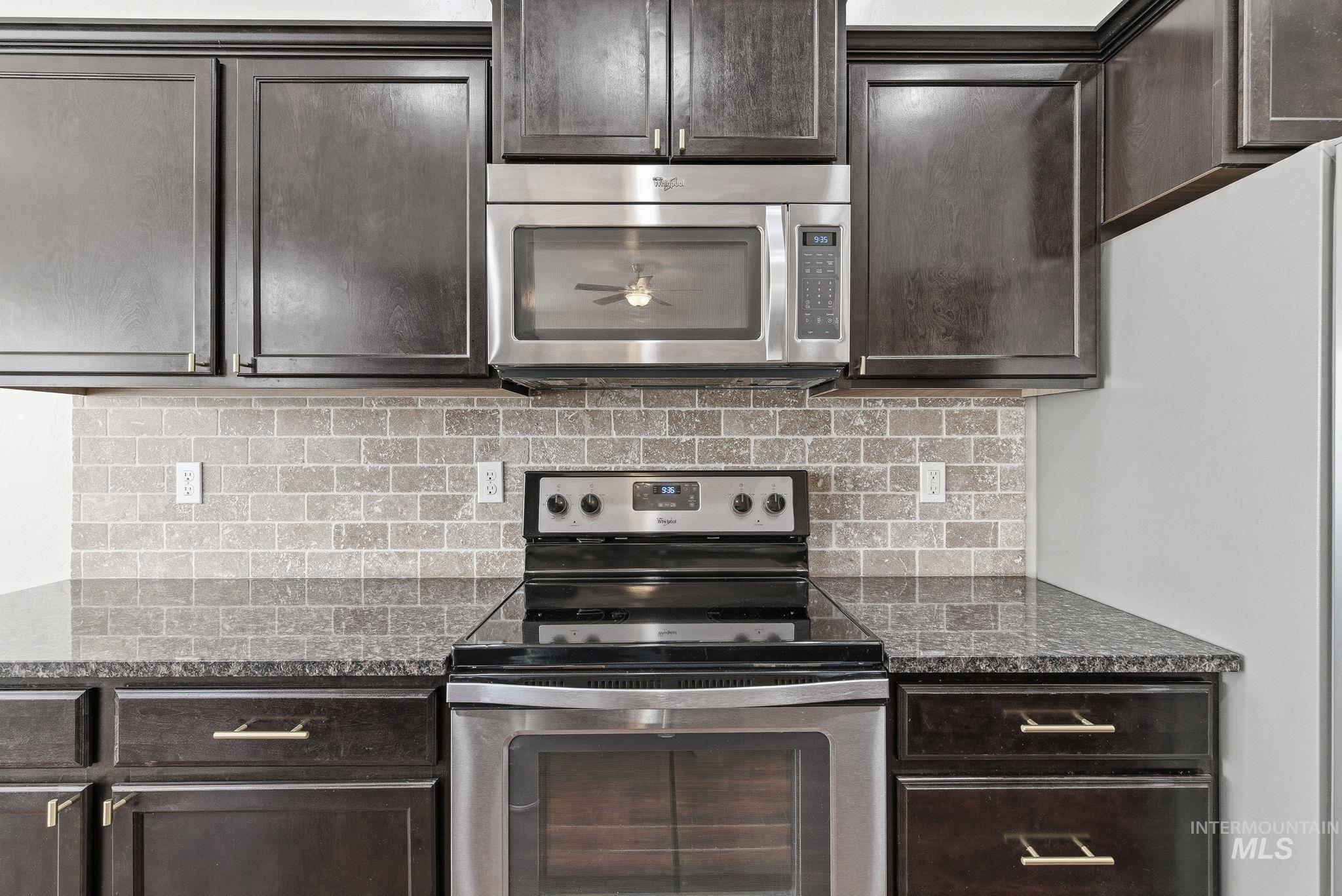 Kitchen with stainless steel appliances, dark stone countertops, and decorative backsplash