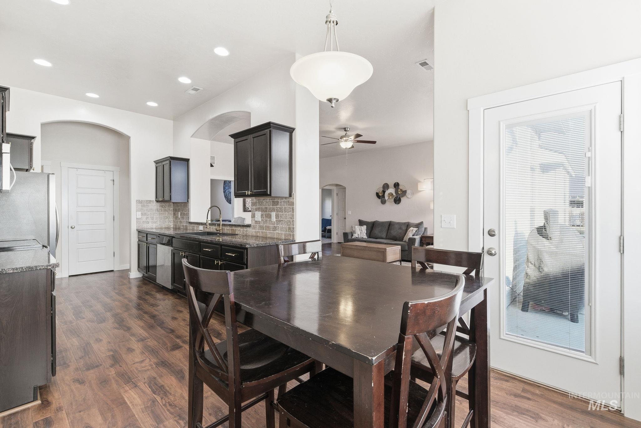 Dining room with arched walkways, ceiling fan, dark wood-style floors, and recessed lighting