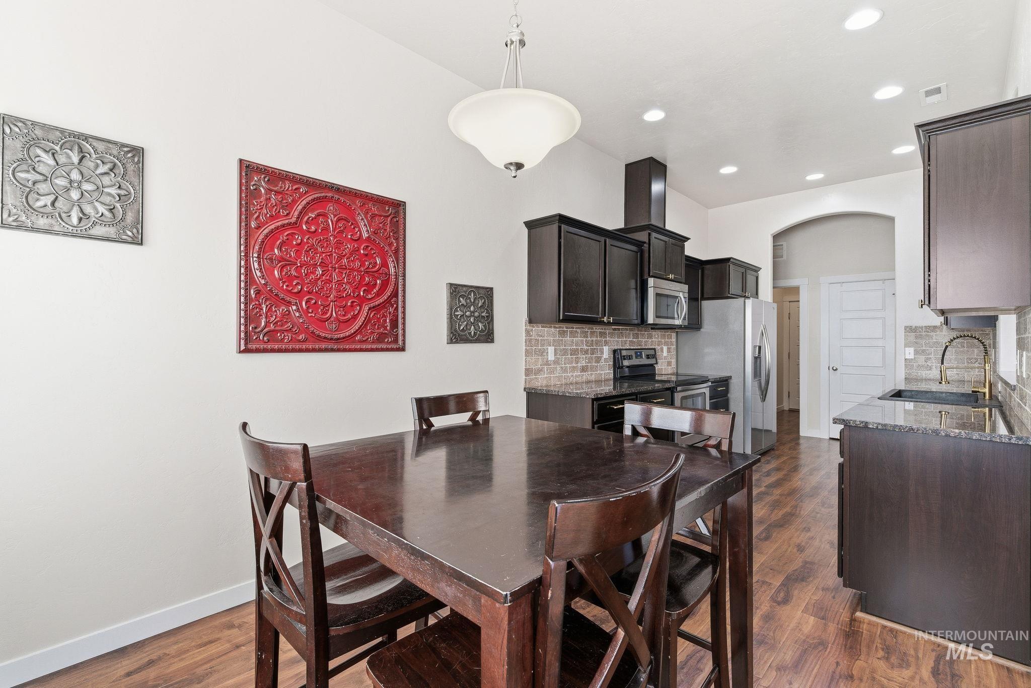 Dining area with arched walkways, dark wood finished floors, and recessed lighting