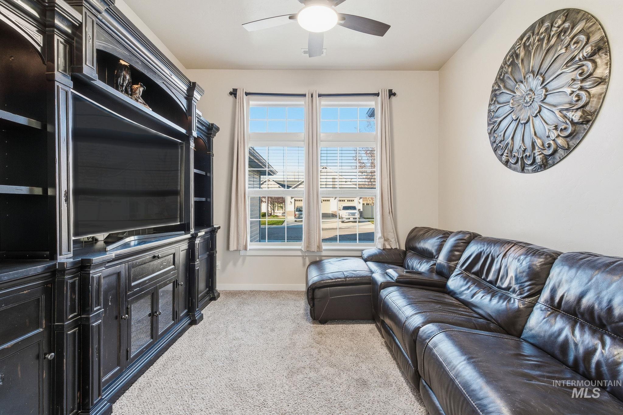 Living area featuring light carpet and ceiling fan