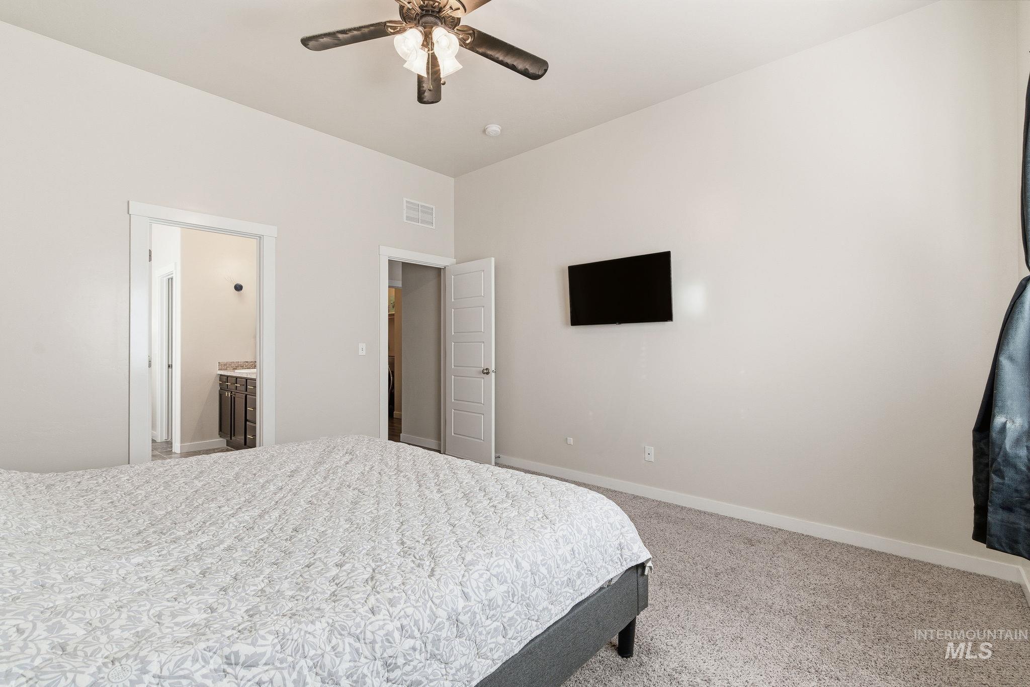 Bedroom with ensuite bath, light colored carpet, and ceiling fan