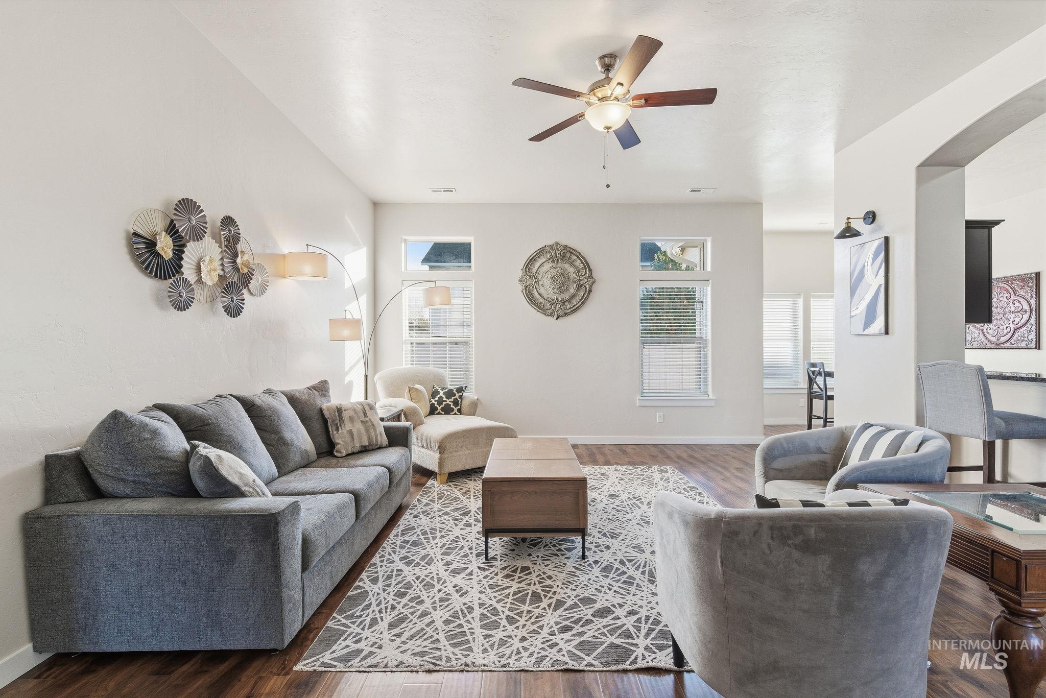 Living area featuring ceiling fan, healthy amount of natural light, wood finished floors, and arched walkways