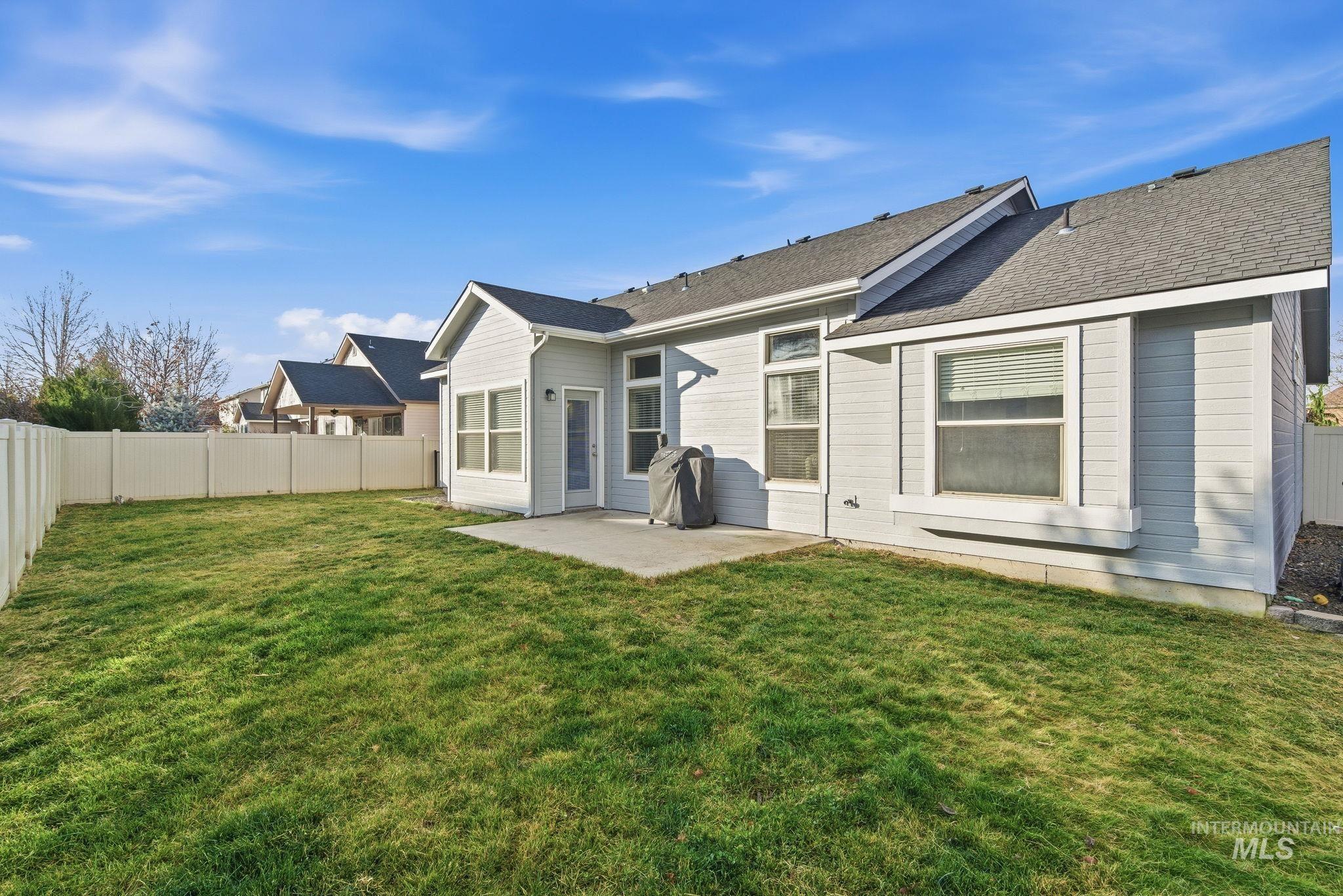Back of house with a patio area, a fenced backyard, and roof with shingles
