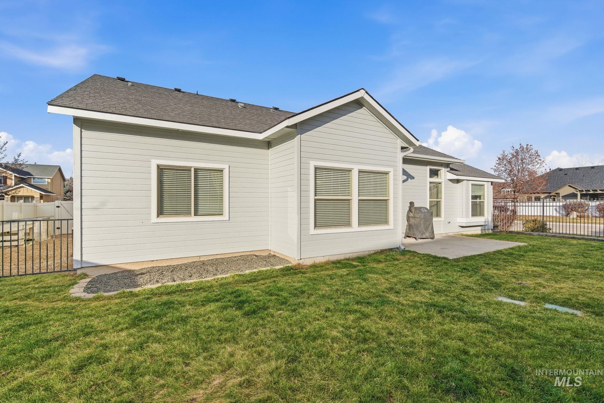 Rear view of house featuring a patio and a shingled roof
