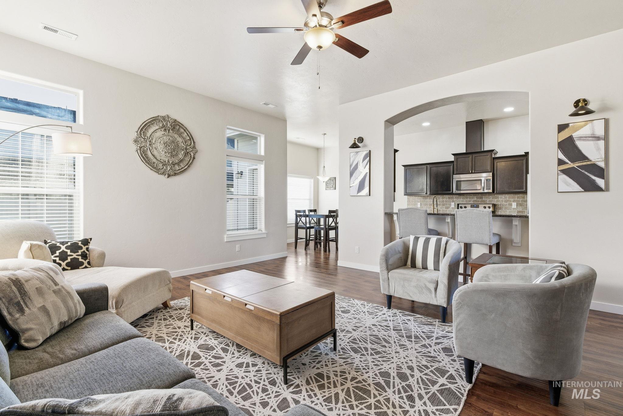 Living area featuring a ceiling fan, dark wood-type flooring, and arched walkways