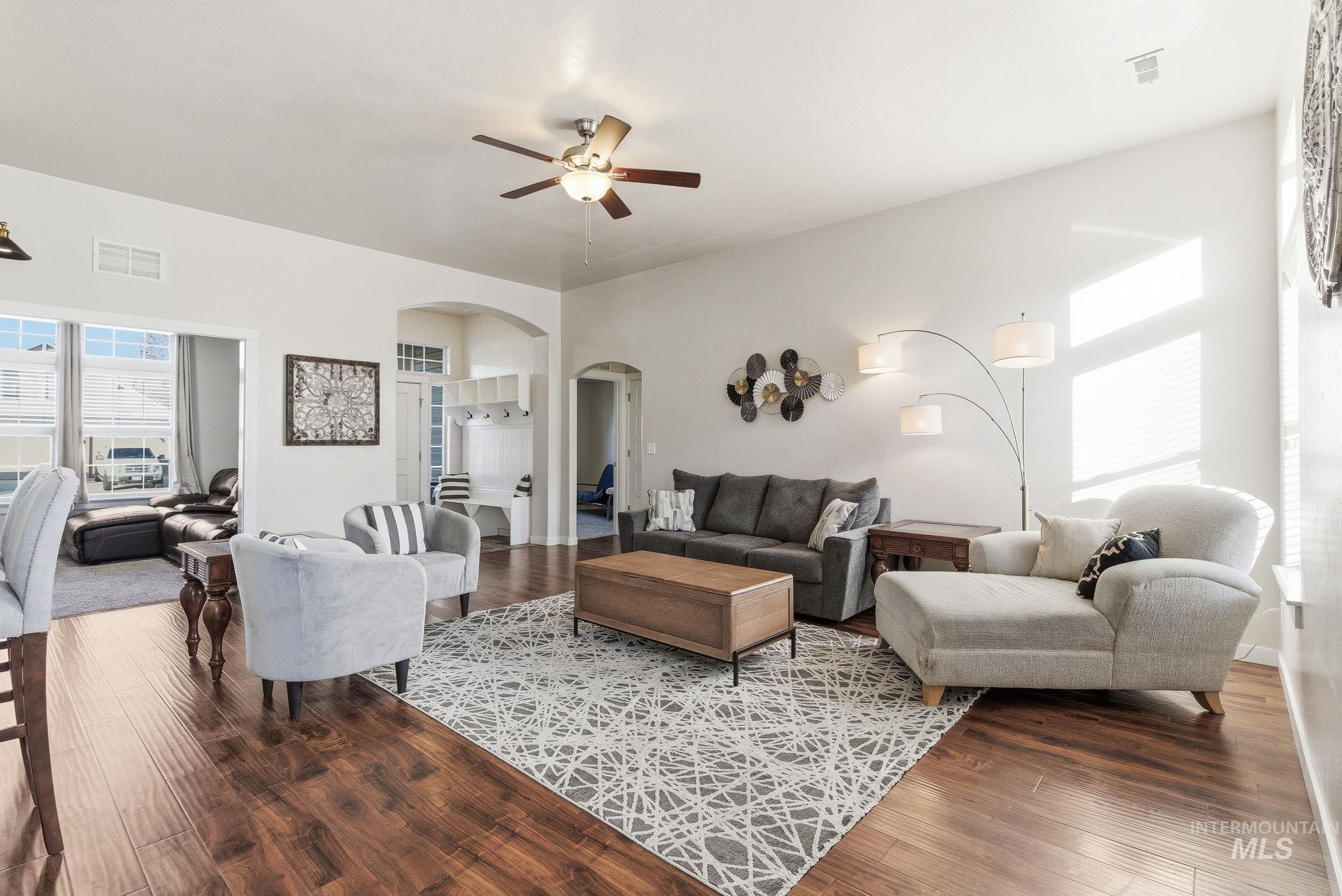 Living room featuring arched walkways, ceiling fan, and dark wood-style floors