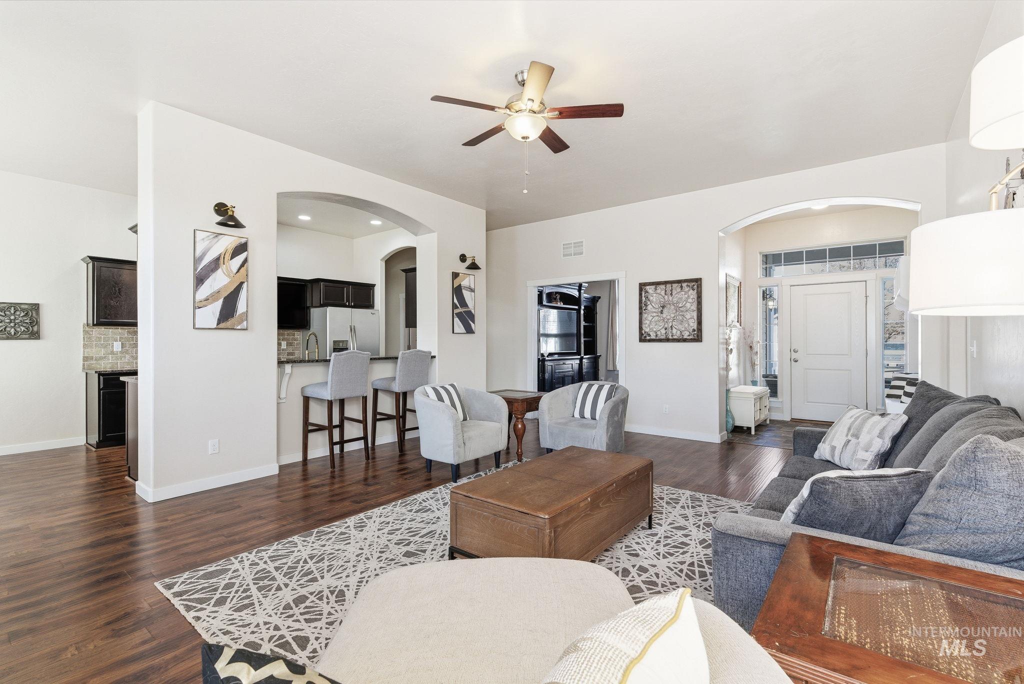 Living area featuring arched walkways, dark wood-type flooring, and ceiling fan
