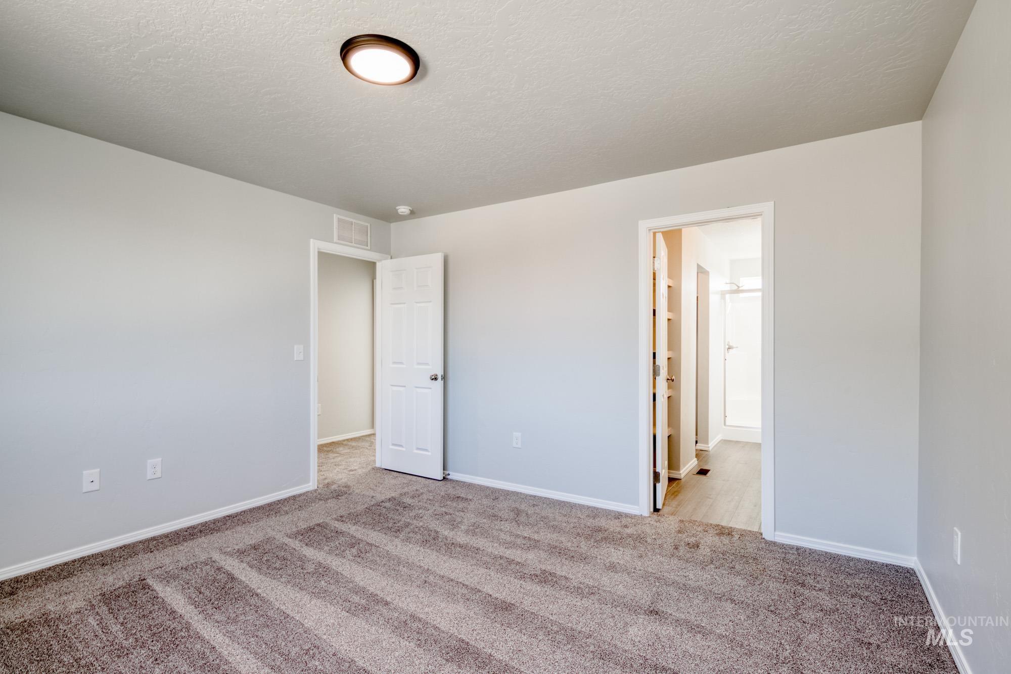 Unfurnished bedroom with carpet, a textured ceiling, and connected bathroom