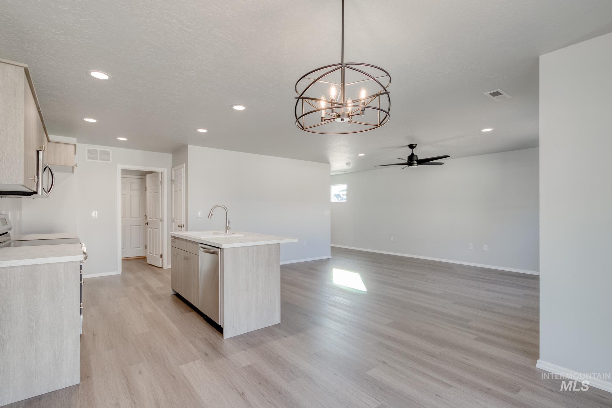 Kitchen with a center island with sink, recessed lighting, a chandelier, ceiling fan, and hanging light fixtures