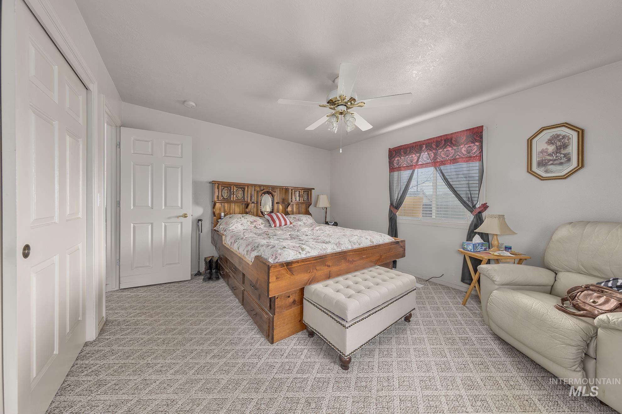 Bedroom with light colored carpet and a ceiling fan