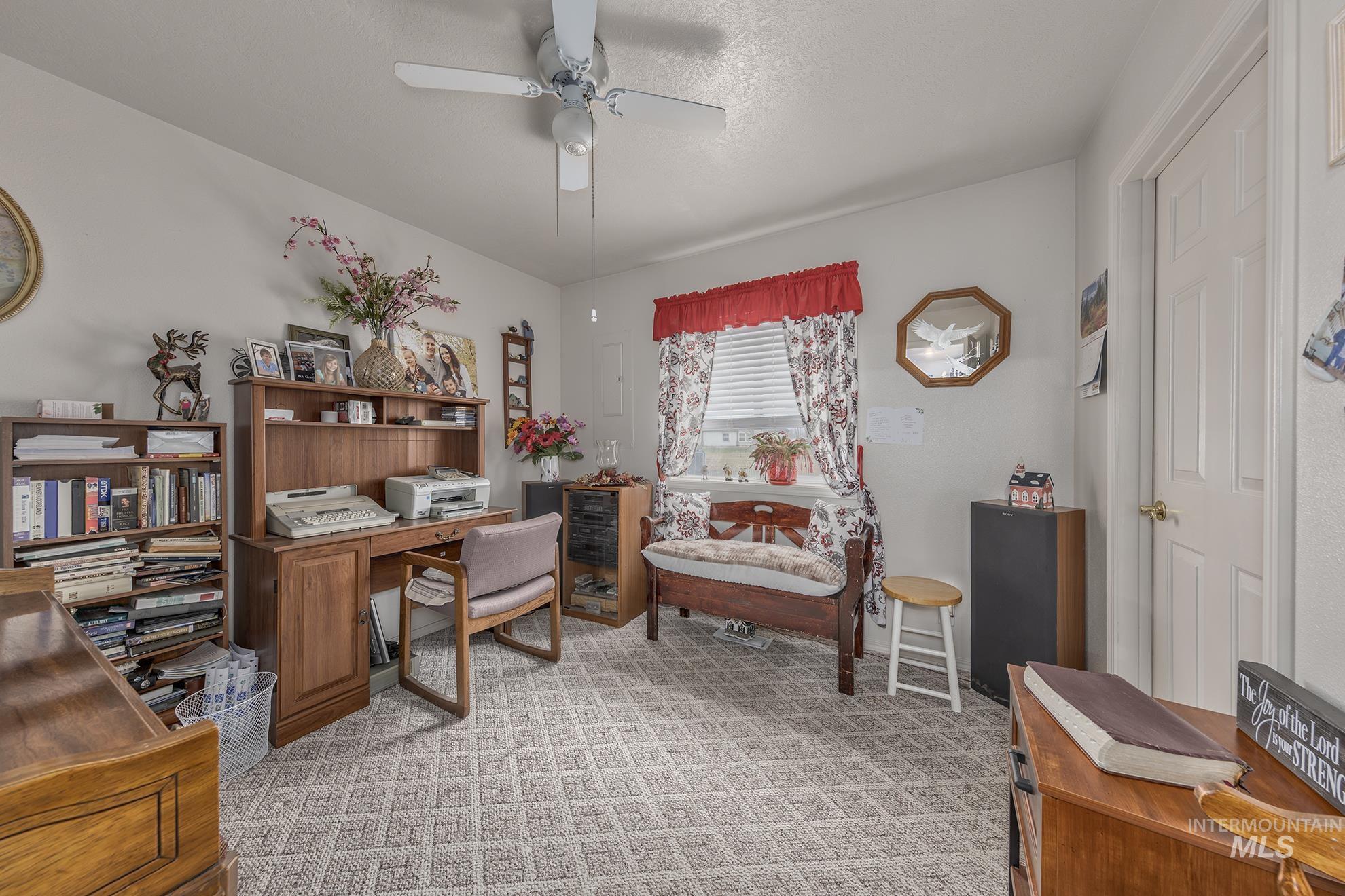 Office area featuring a ceiling fan, light carpet, and a textured ceiling