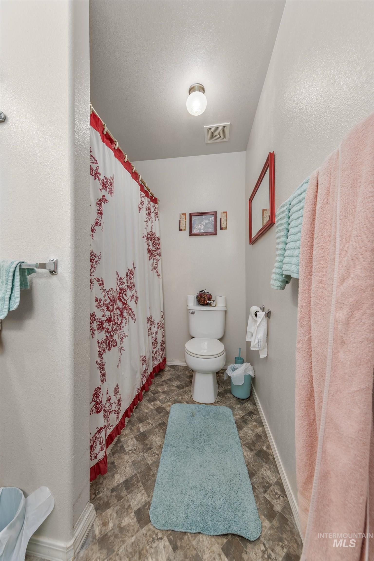 Bathroom featuring a shower with curtain and toilet