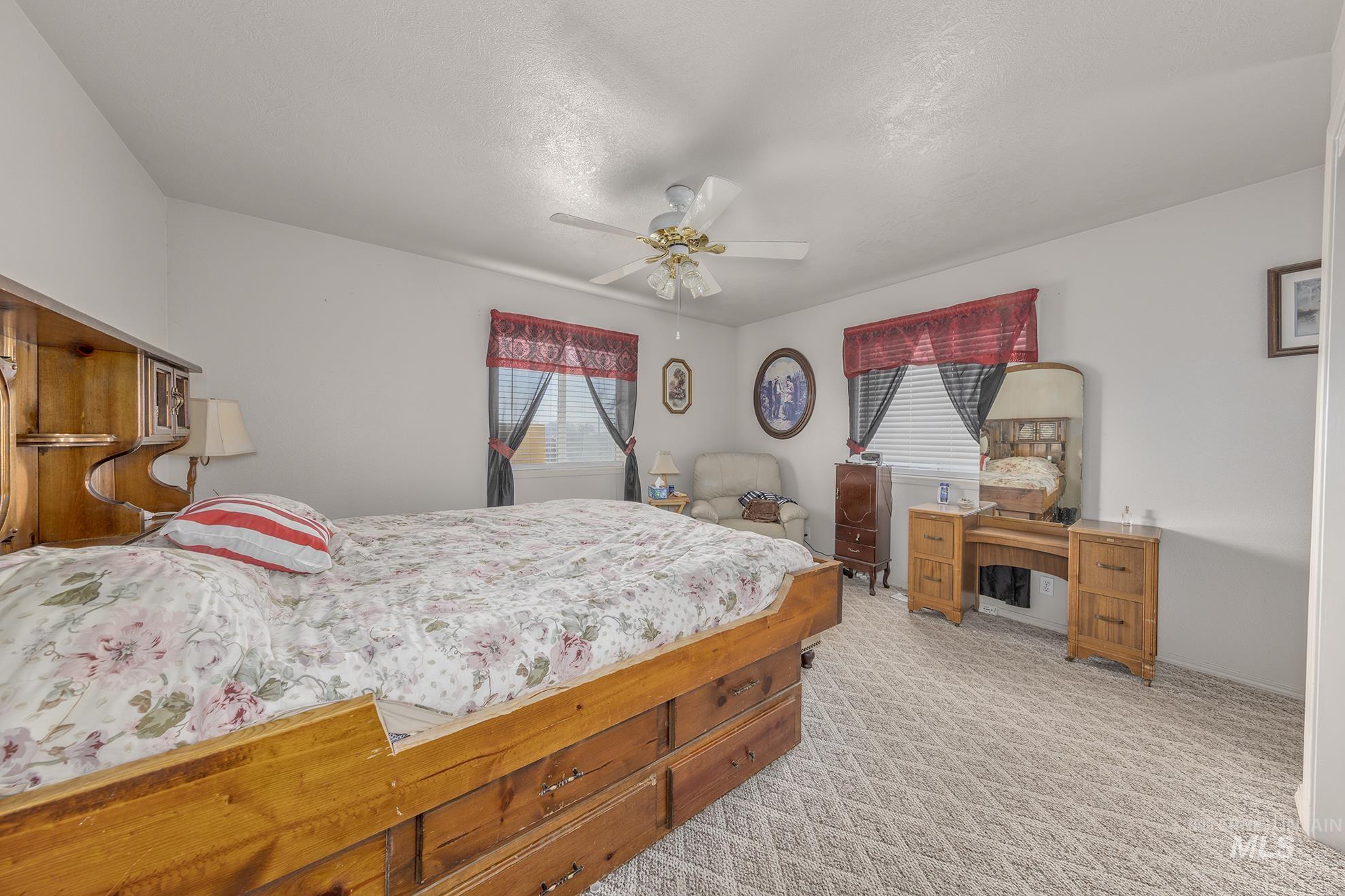 Bedroom with a ceiling fan, light colored carpet, and a textured ceiling