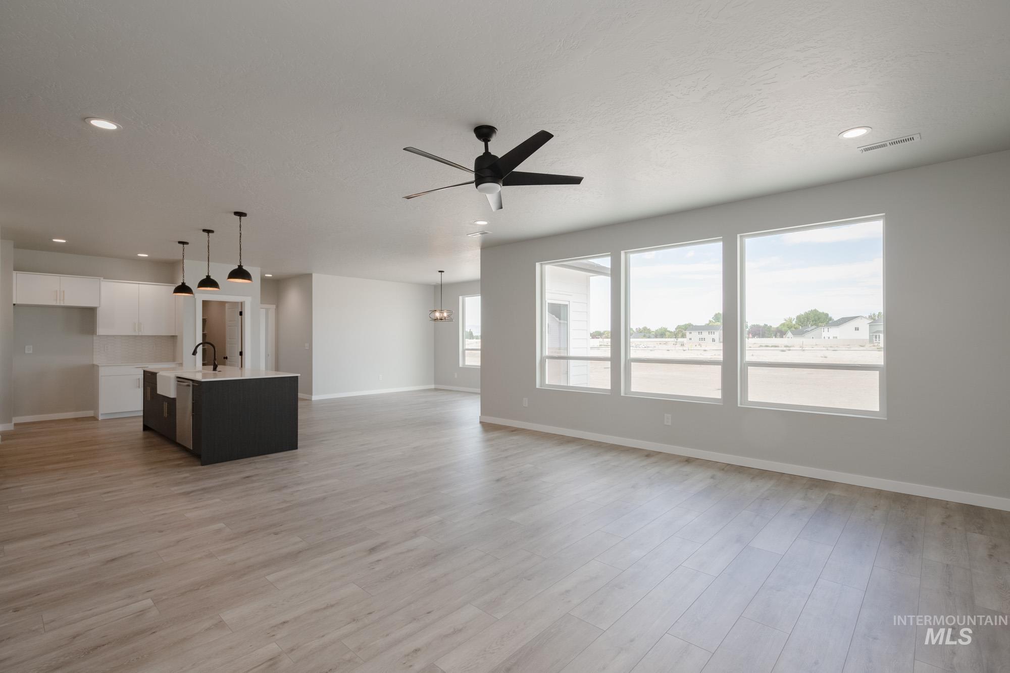 Unfurnished living room featuring a ceiling fan, recessed lighting, light wood-style flooring, and a chandelier