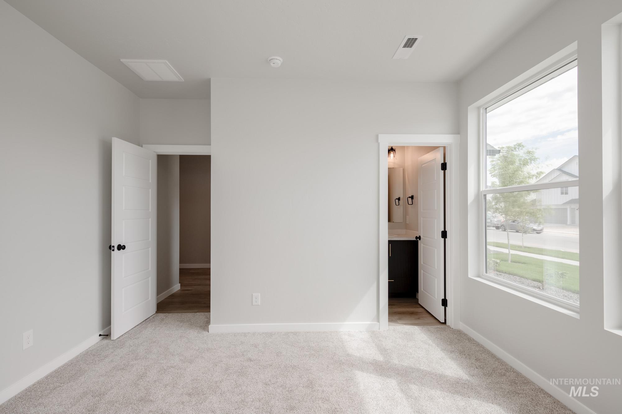 Unfurnished bedroom featuring light colored carpet and ensuite bathroom
