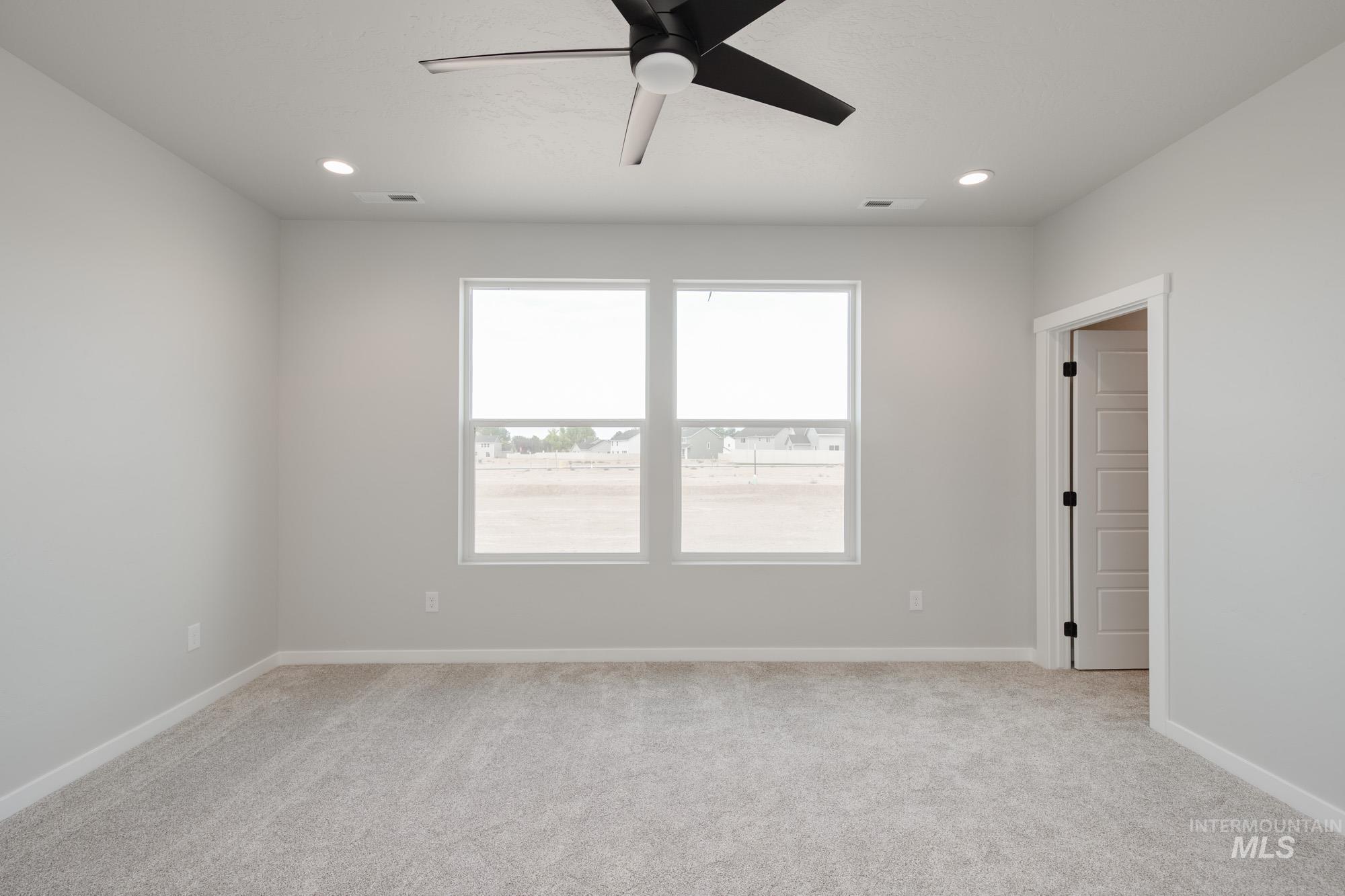 Empty room featuring light carpet, a ceiling fan, and recessed lighting