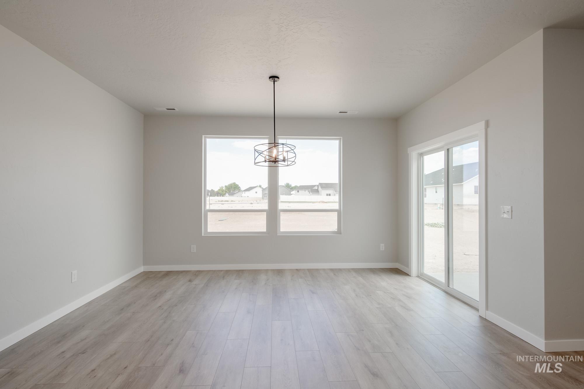 Unfurnished dining area featuring light wood-type flooring and a chandelier