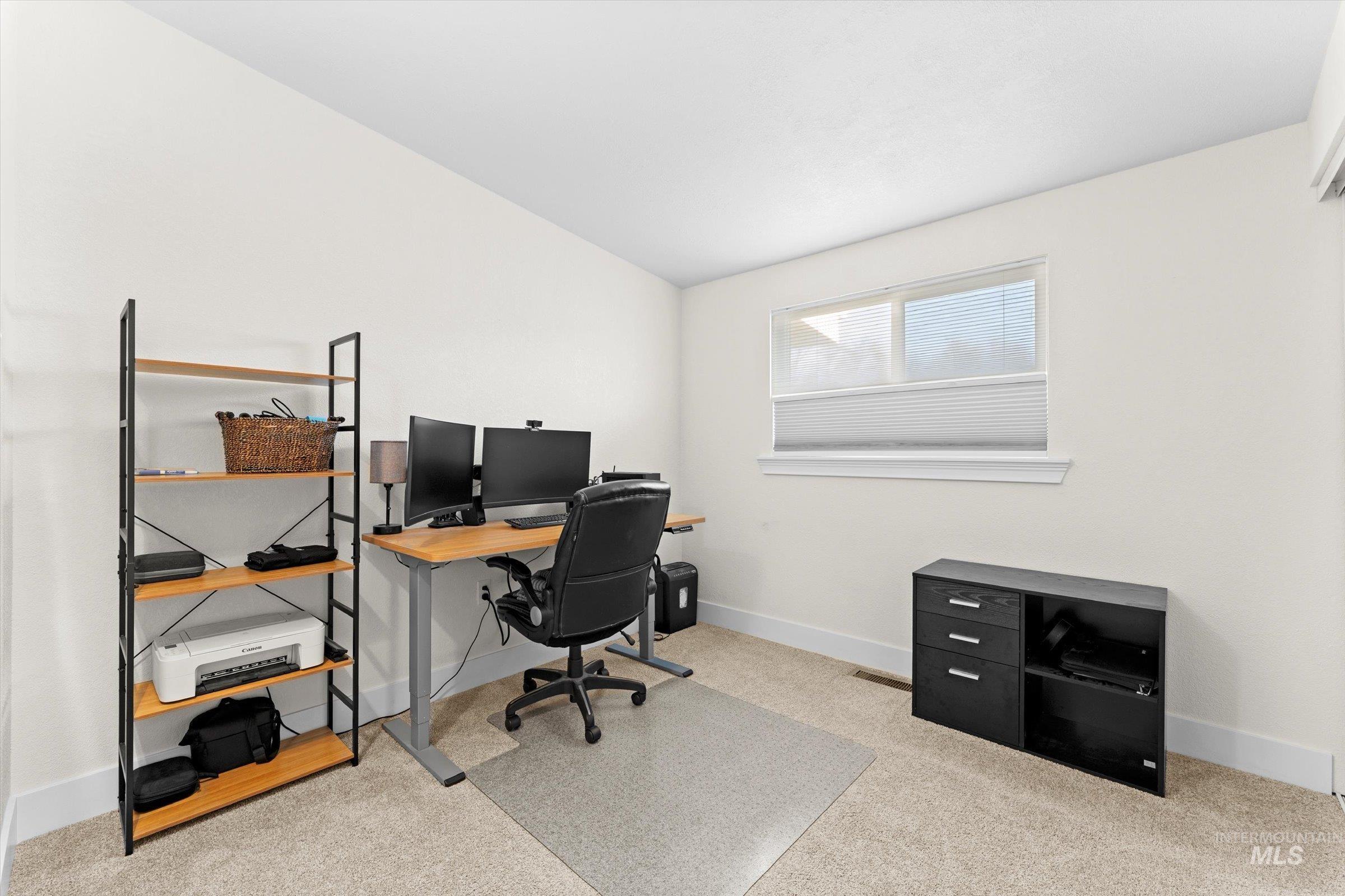 Bedroom but currently used as an office area featuring baseboards and light carpet
