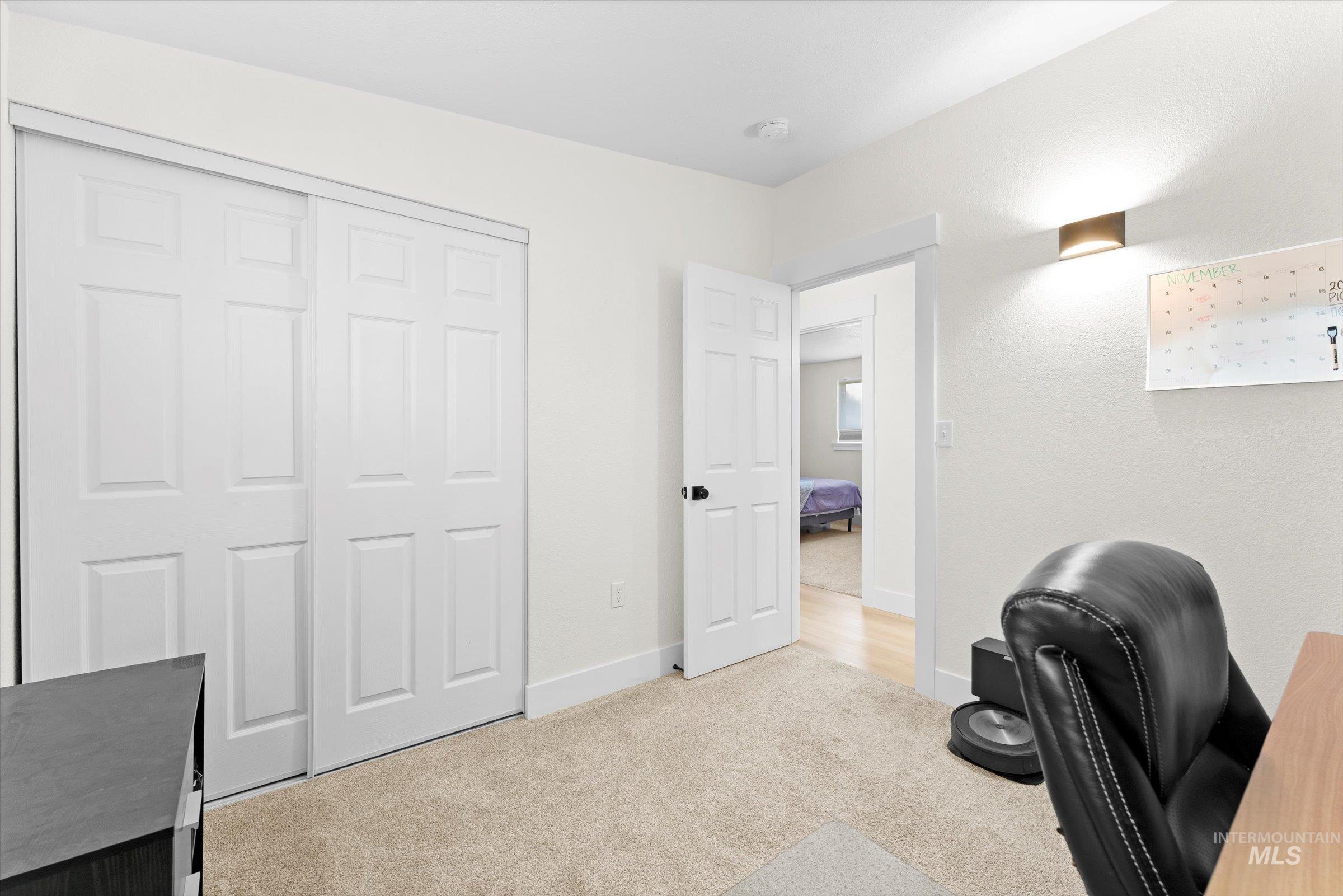 Bedroom but currently being used as an office featuring light colored carpet and baseboards
