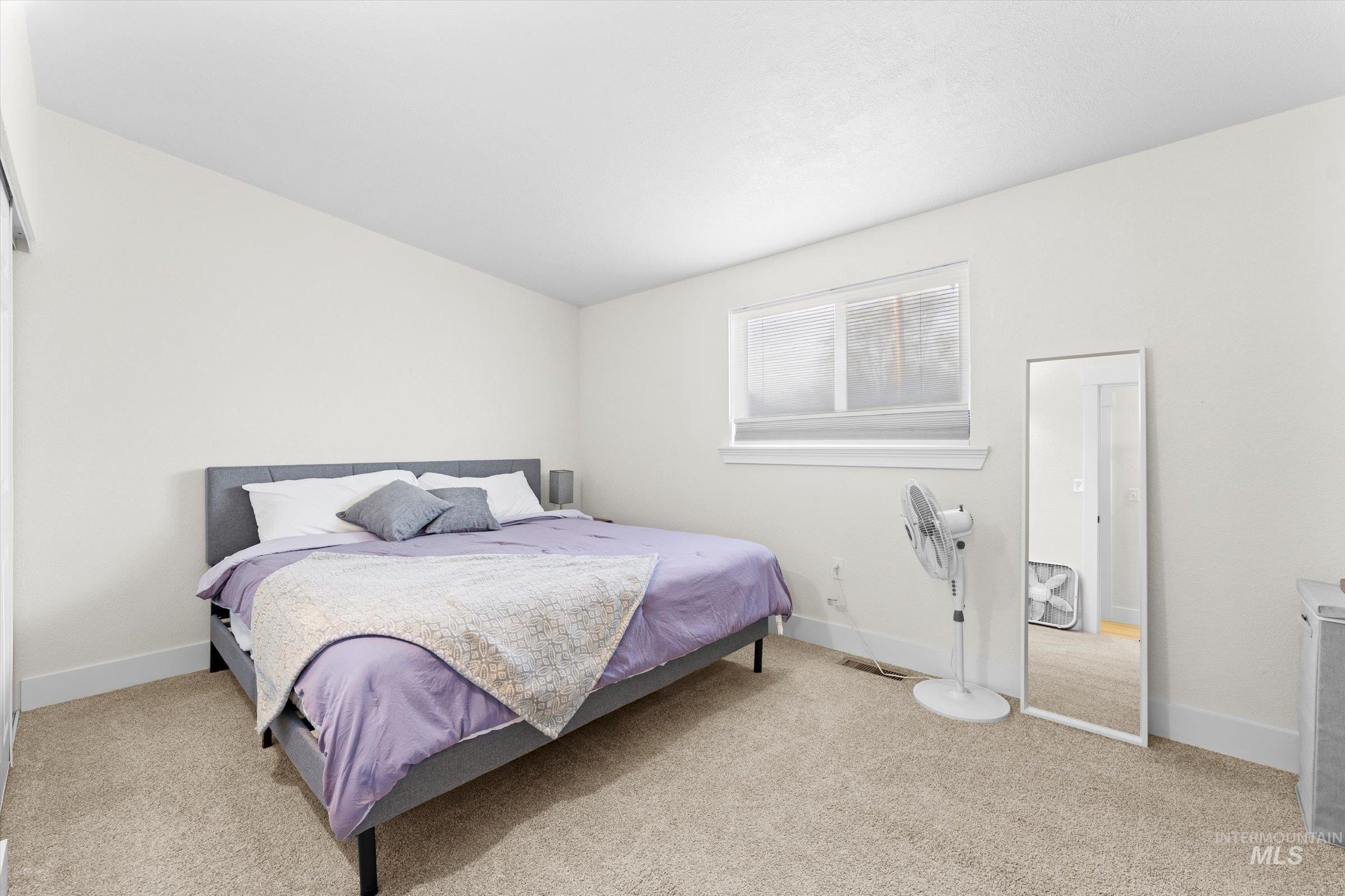 Bedroom with light colored carpet and baseboards