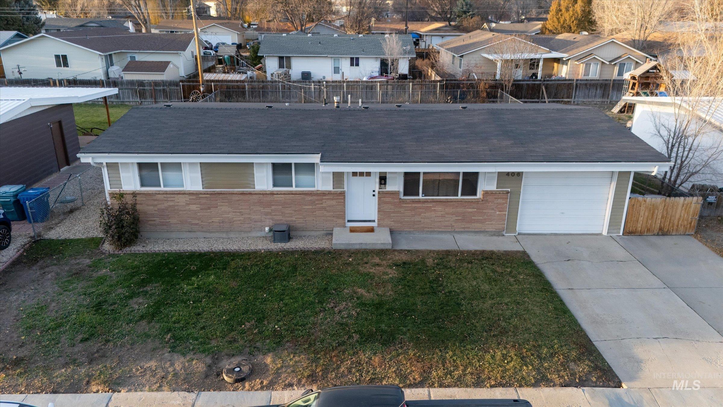Ranch-style home with brick siding, driveway, an attached garage, and a residential view