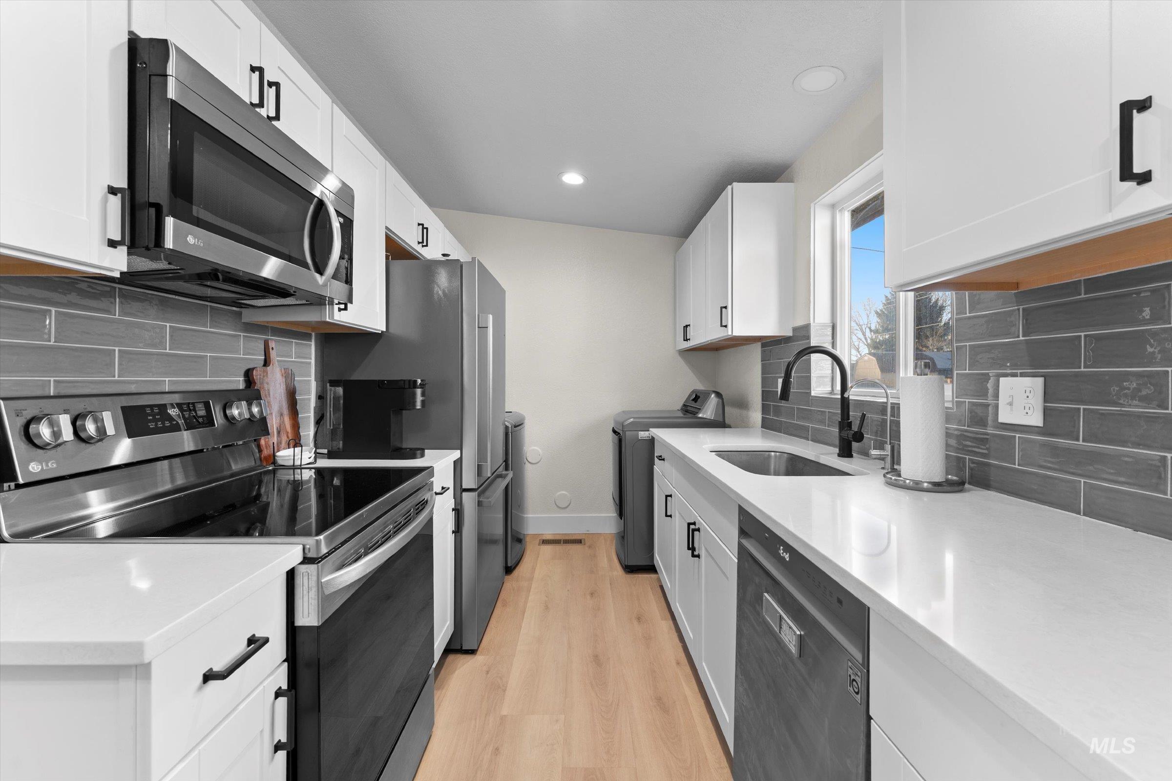 Kitchen featuring stainless steel appliances, tasteful backsplash, washer / clothes dryer, light stone counters, and recessed lighting