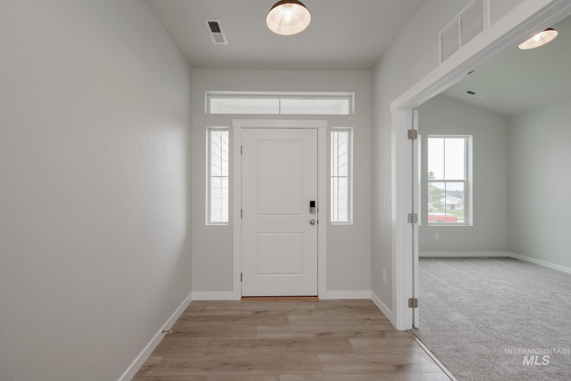 Entrance foyer with plenty of natural light, light wood finished floors, and light colored carpet