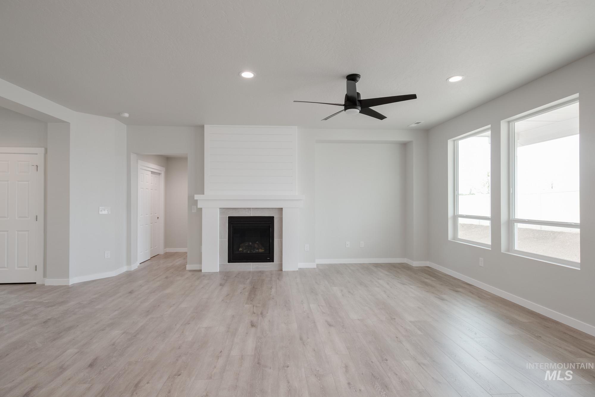 Unfurnished living room with a tile fireplace, light wood-style flooring, ceiling fan, and recessed lighting