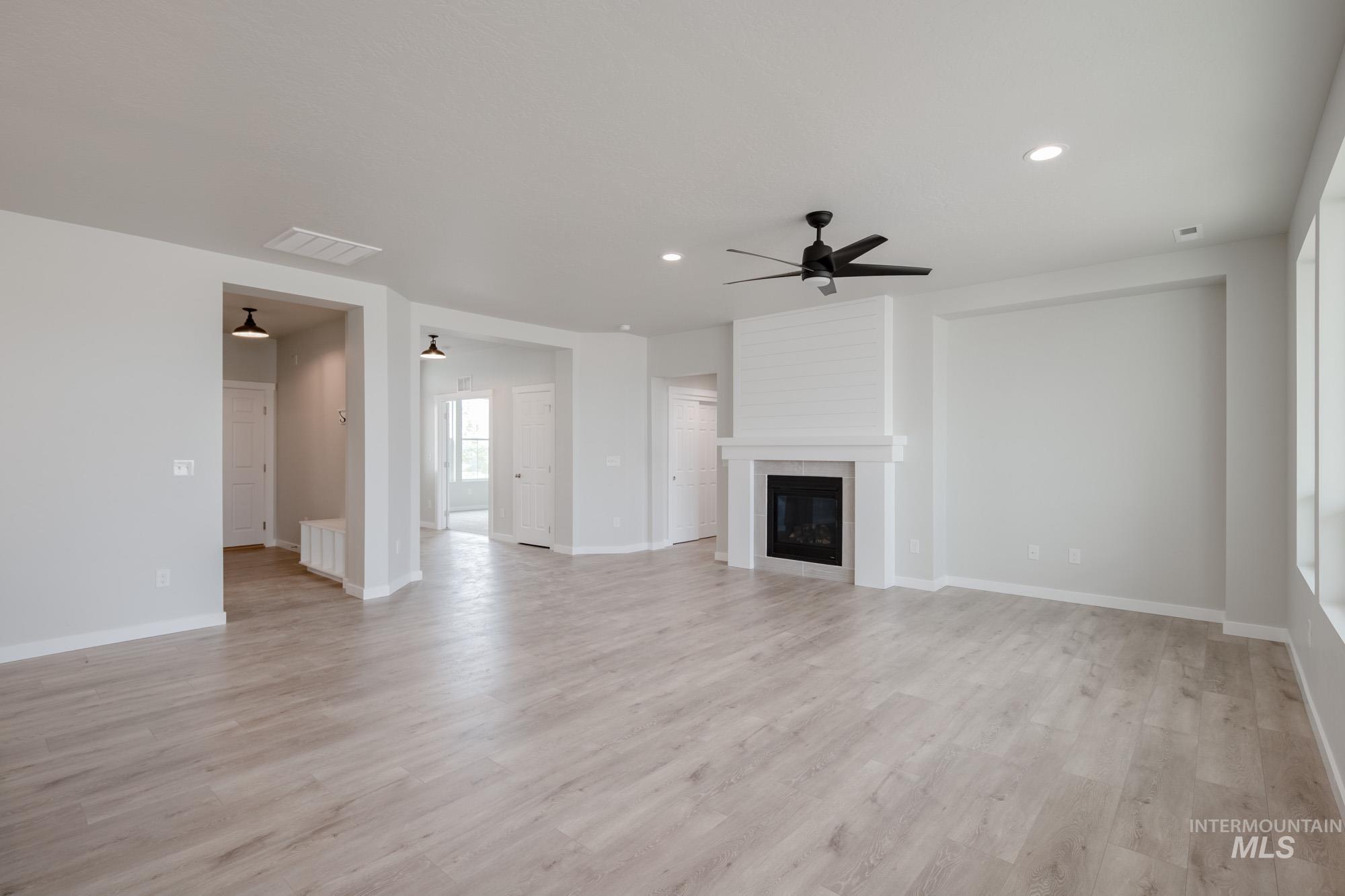 Unfurnished living room with a ceiling fan, light wood-style floors, a fireplace, and recessed lighting