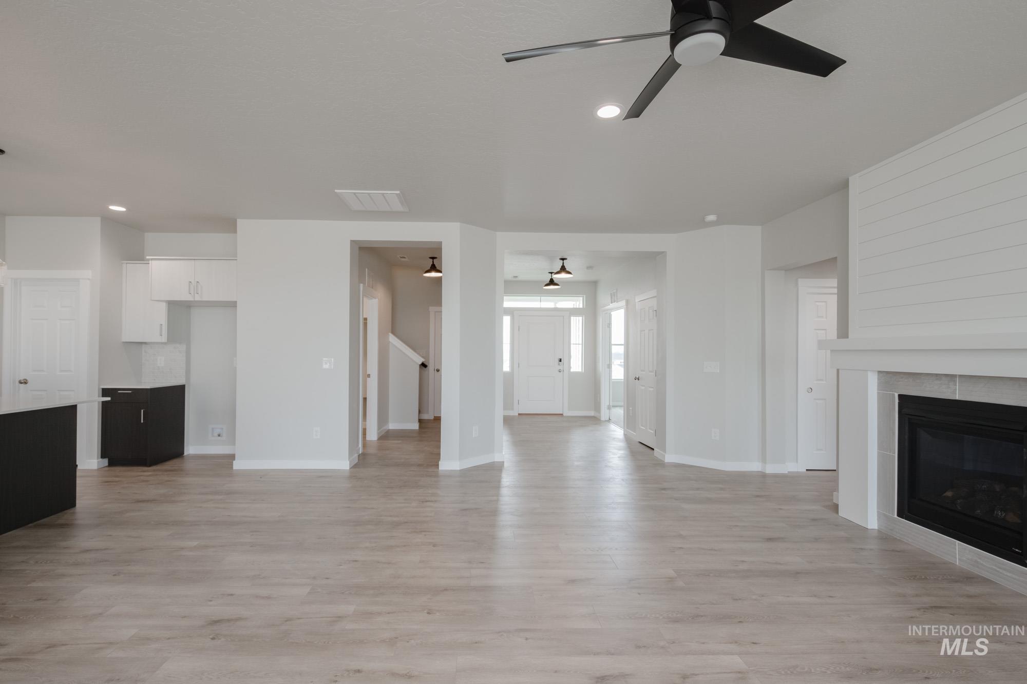 Unfurnished living room featuring a ceiling fan, light wood-style flooring, recessed lighting, and a fireplace
