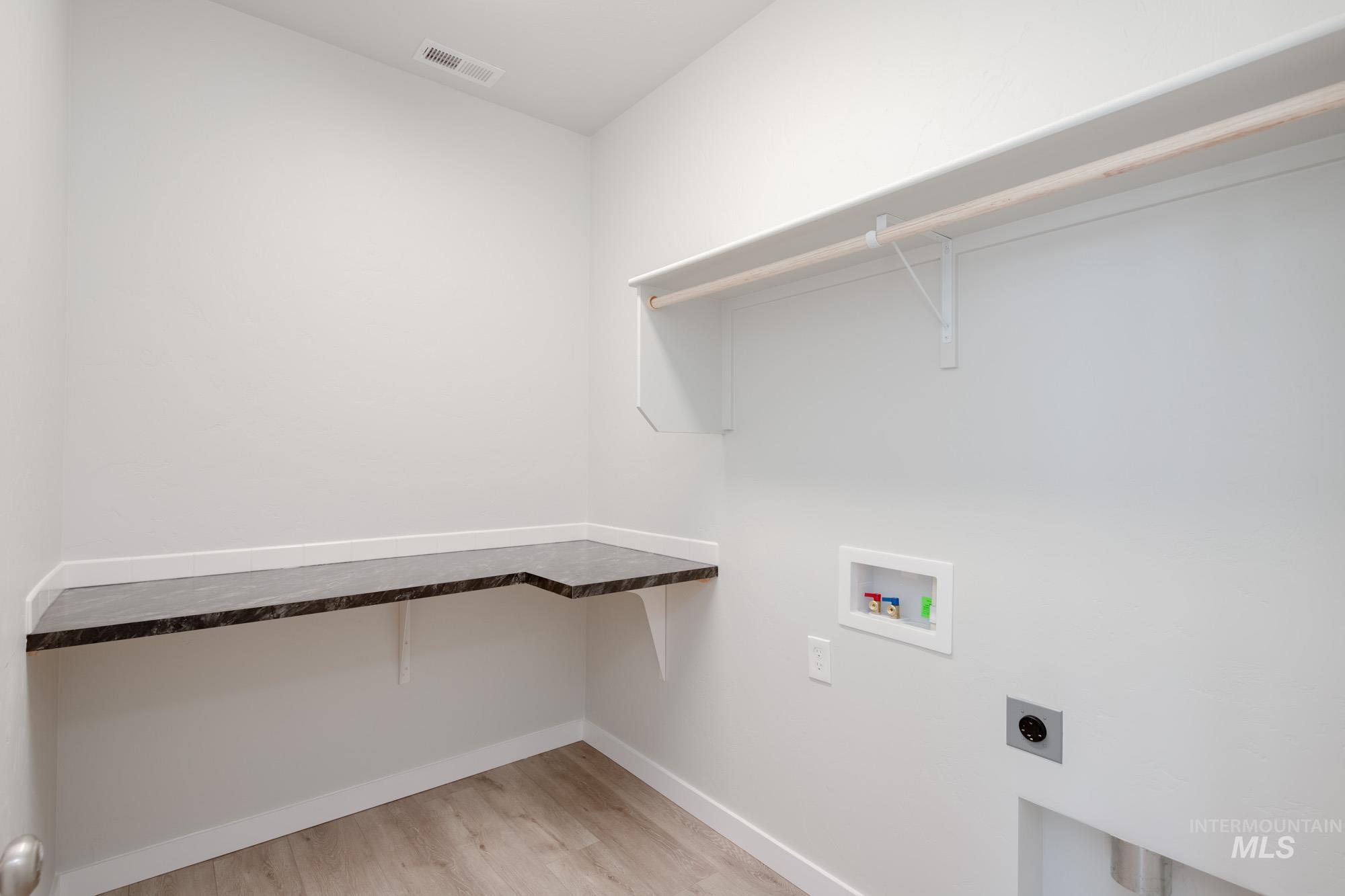 Washroom with light wood-style floors, washer hookup, and hookup for an electric dryer