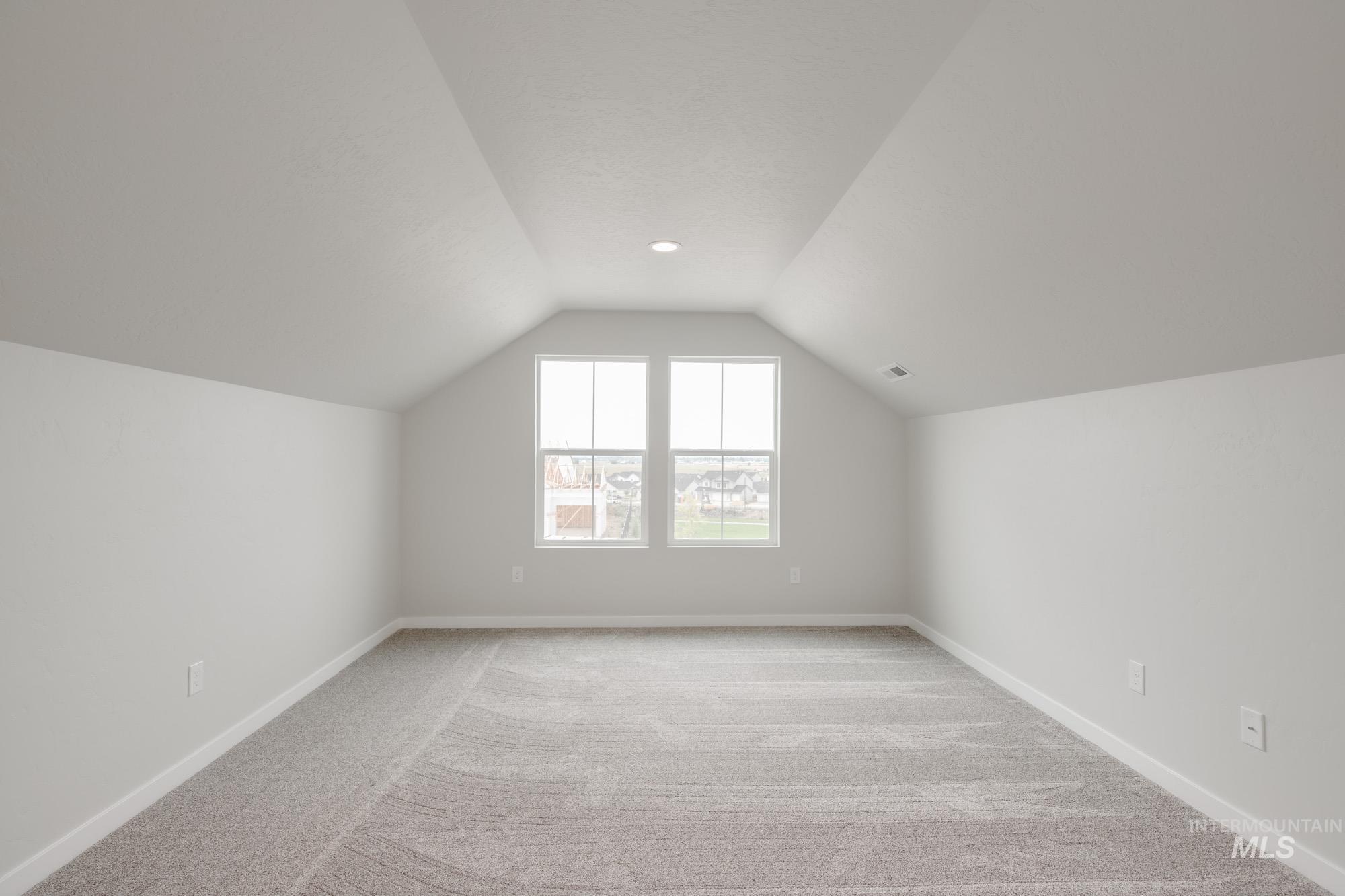 Bonus room featuring vaulted ceiling and light carpet