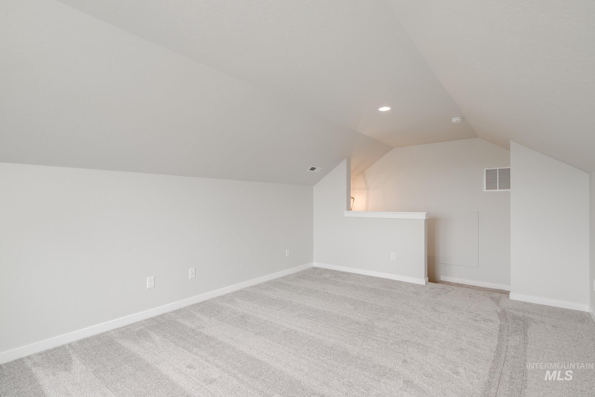 Bonus room featuring vaulted ceiling and light carpet