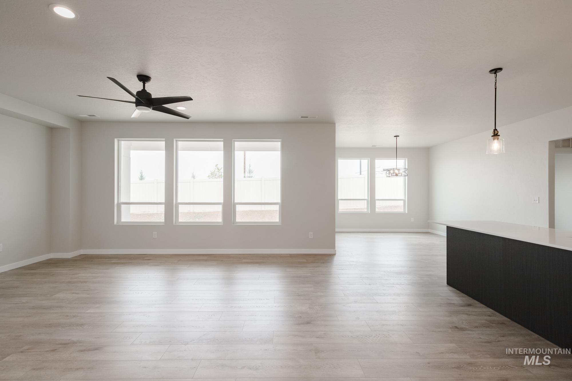 Spare room featuring ceiling fan, light wood-style floors, and a chandelier