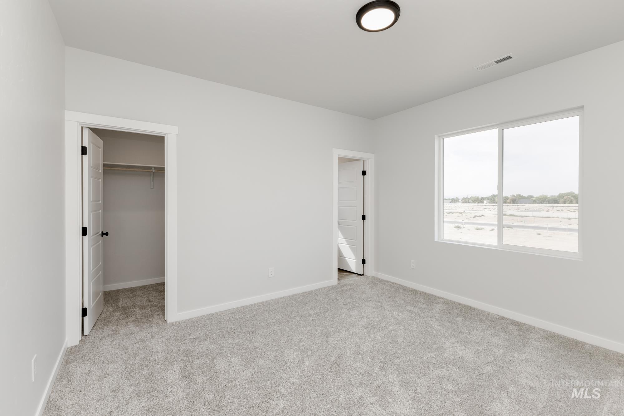 Unfurnished bedroom with a spacious closet and light colored carpet
