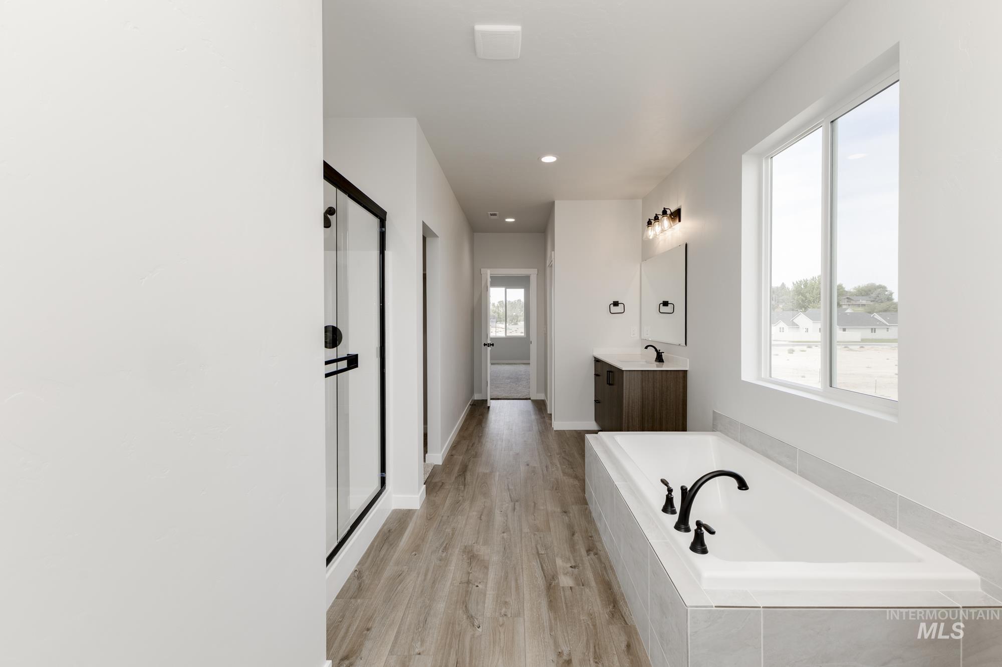 Bathroom featuring a bath, light wood-type flooring, vanity, recessed lighting, and a stall shower