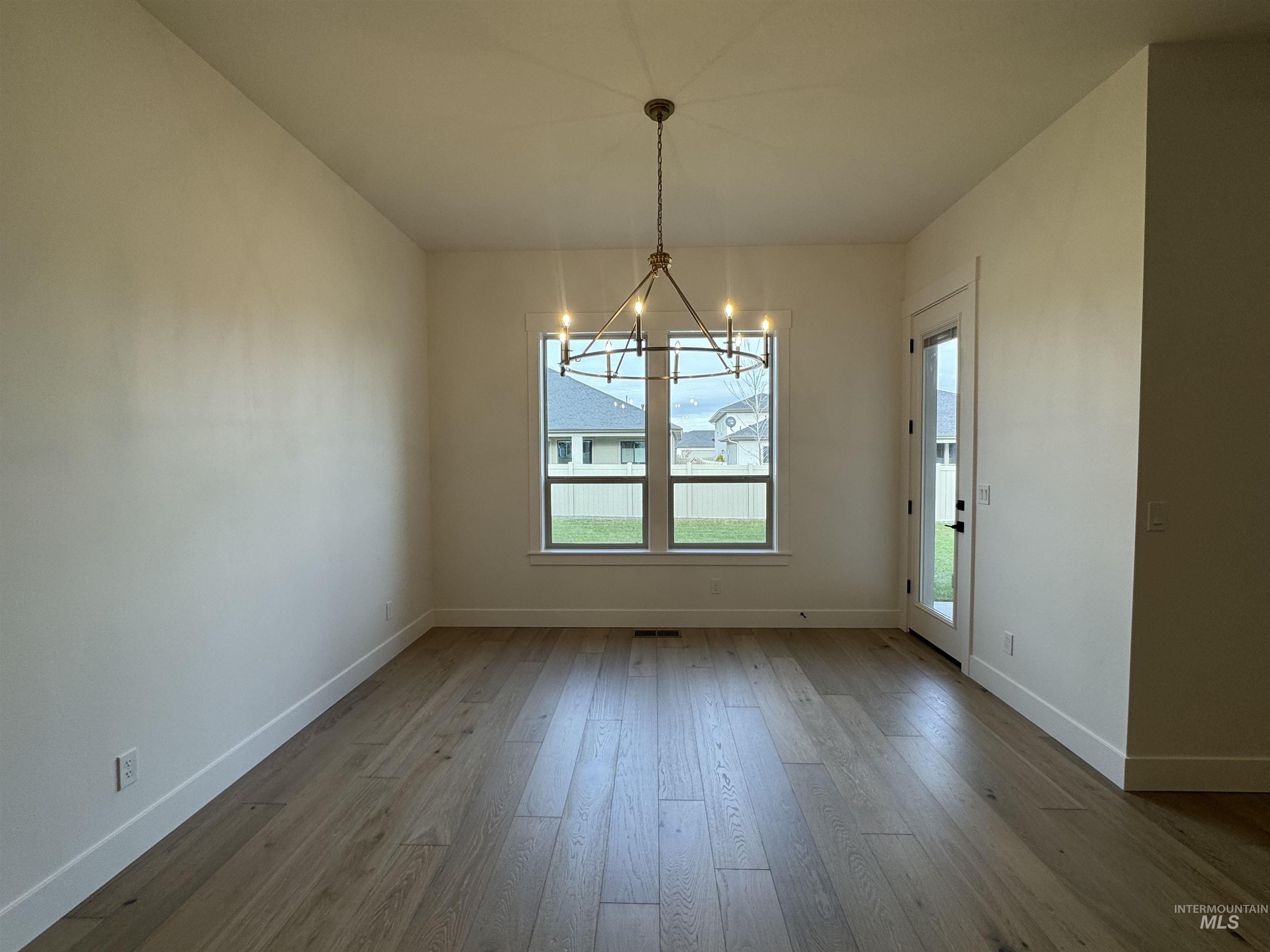Unfurnished dining area featuring a chandelier and light wood-style flooring