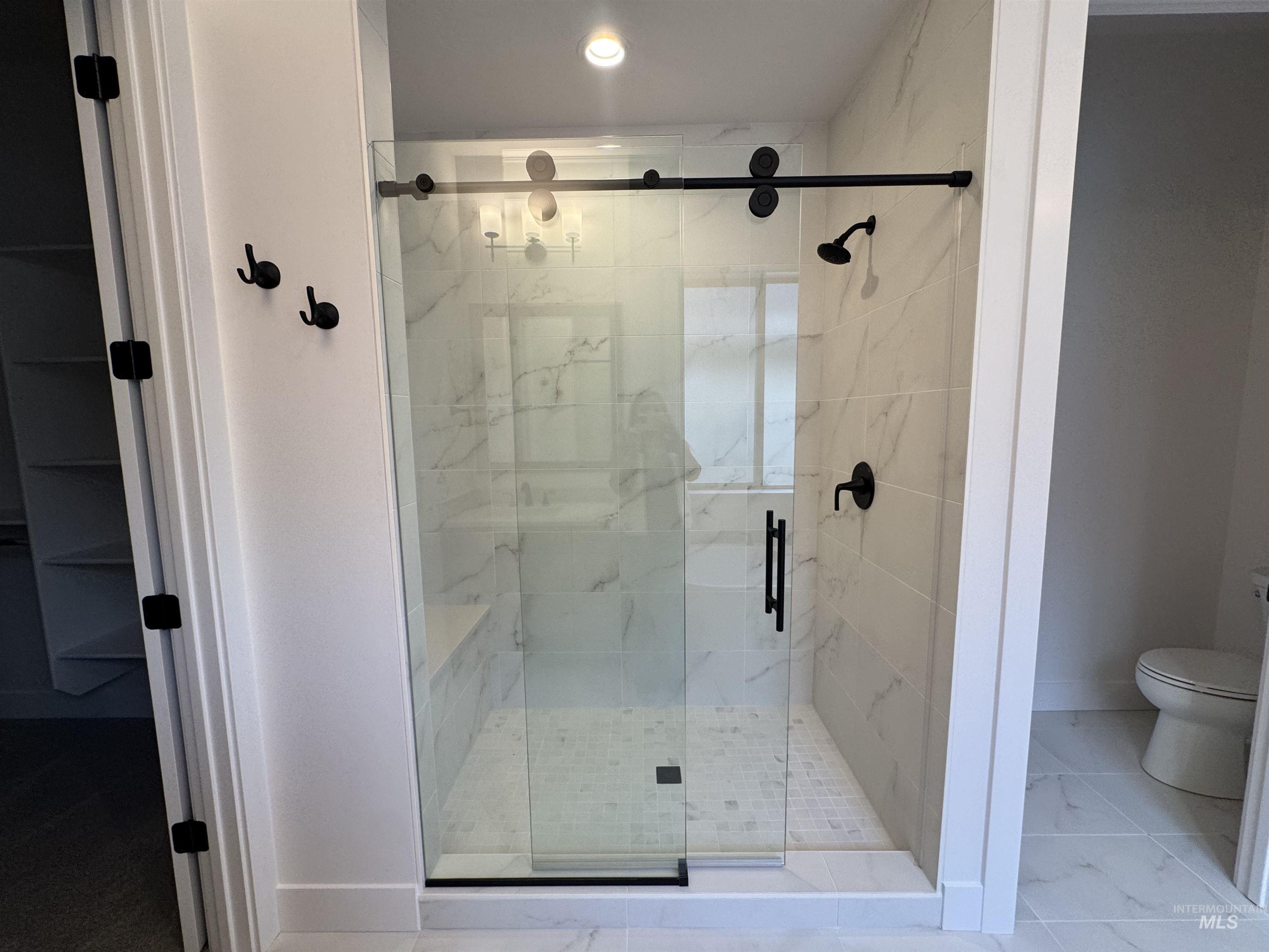 Full bathroom with a marble finish shower and baseboards