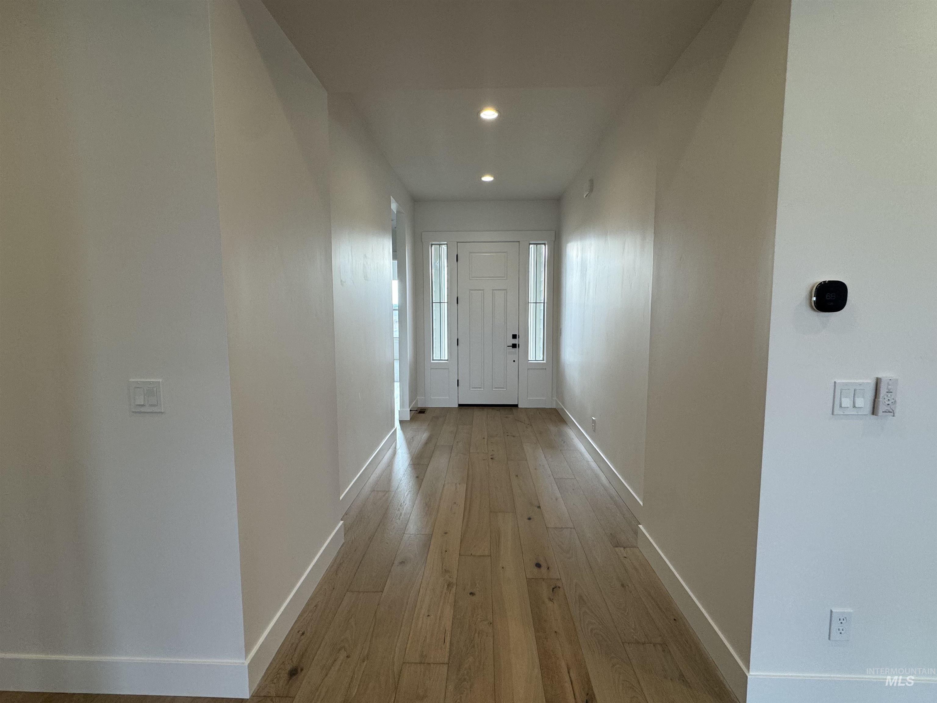 Corridor with light wood-style flooring and recessed lighting