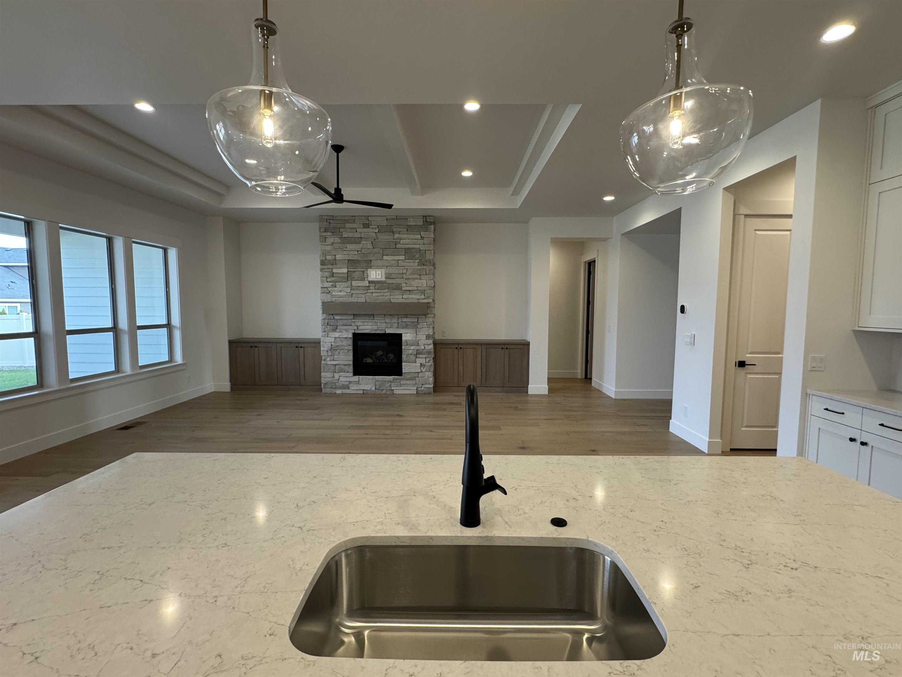 Kitchen with light stone countertops, decorative light fixtures, open floor plan, recessed lighting, and a stone fireplace