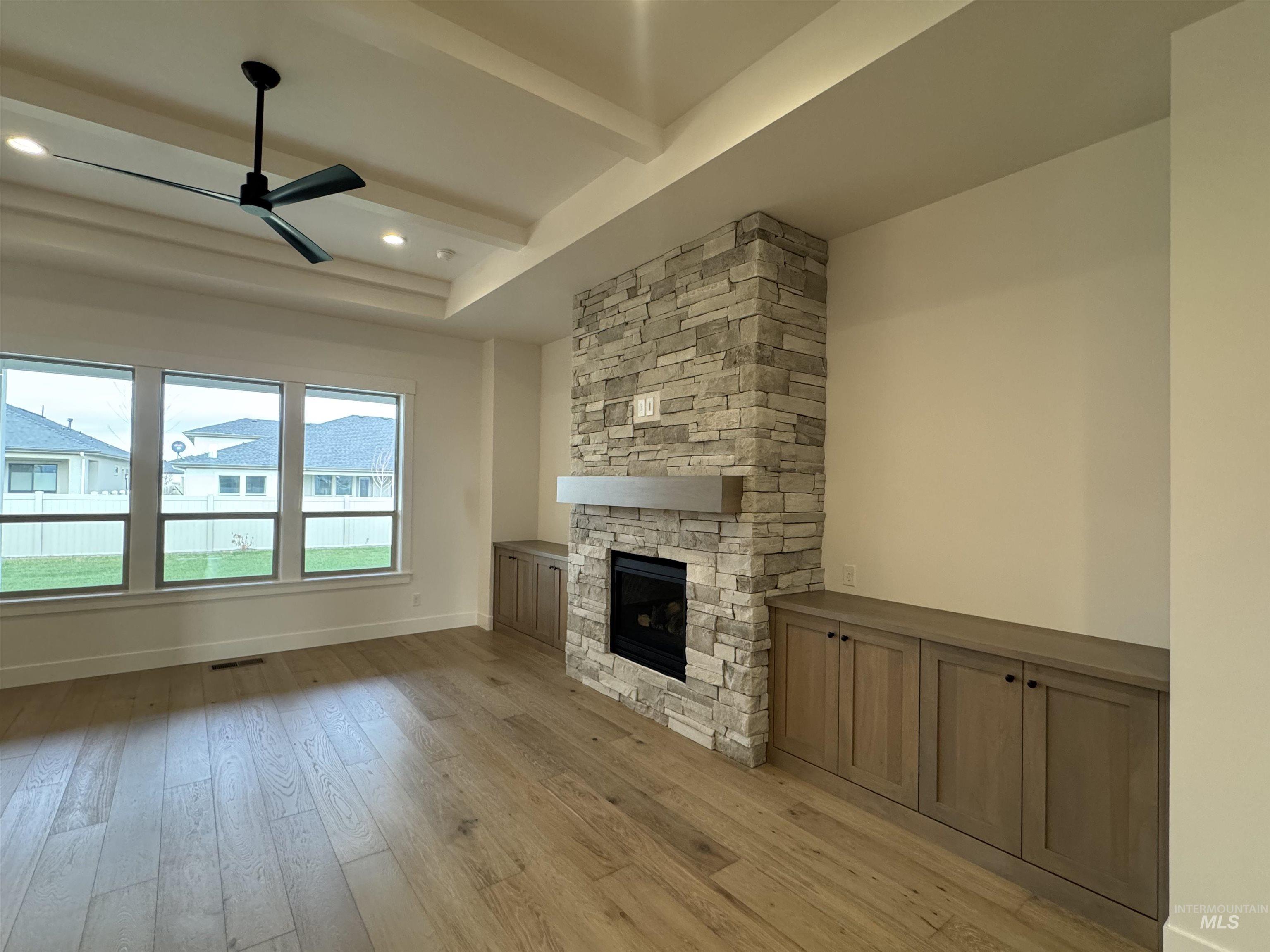 Unfurnished living room featuring light wood finished floors, beam ceiling, a fireplace, ceiling fan, and recessed lighting