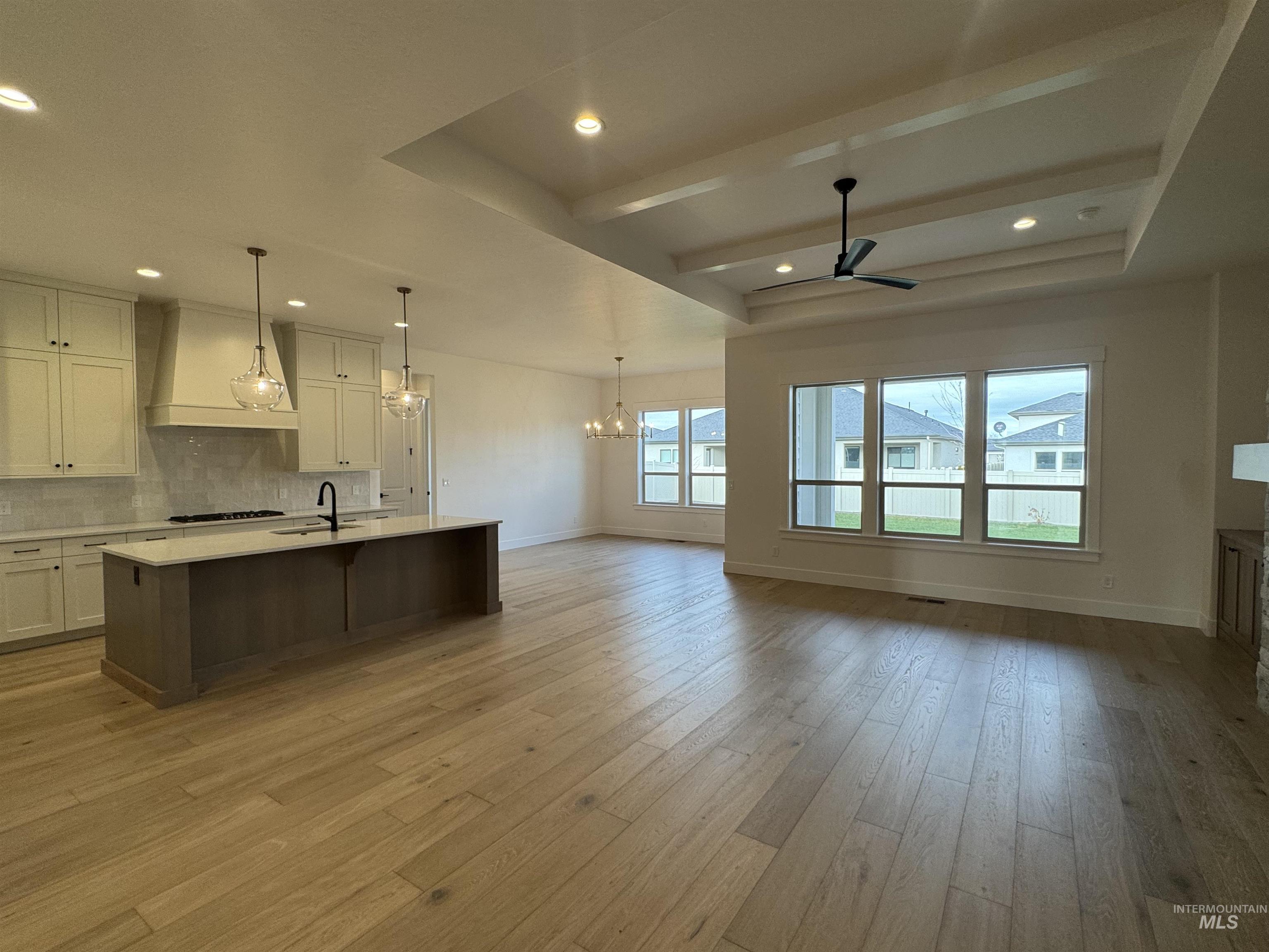 Kitchen featuring white cabinetry, tasteful backsplash, a center island with sink, open floor plan, and a chandelier