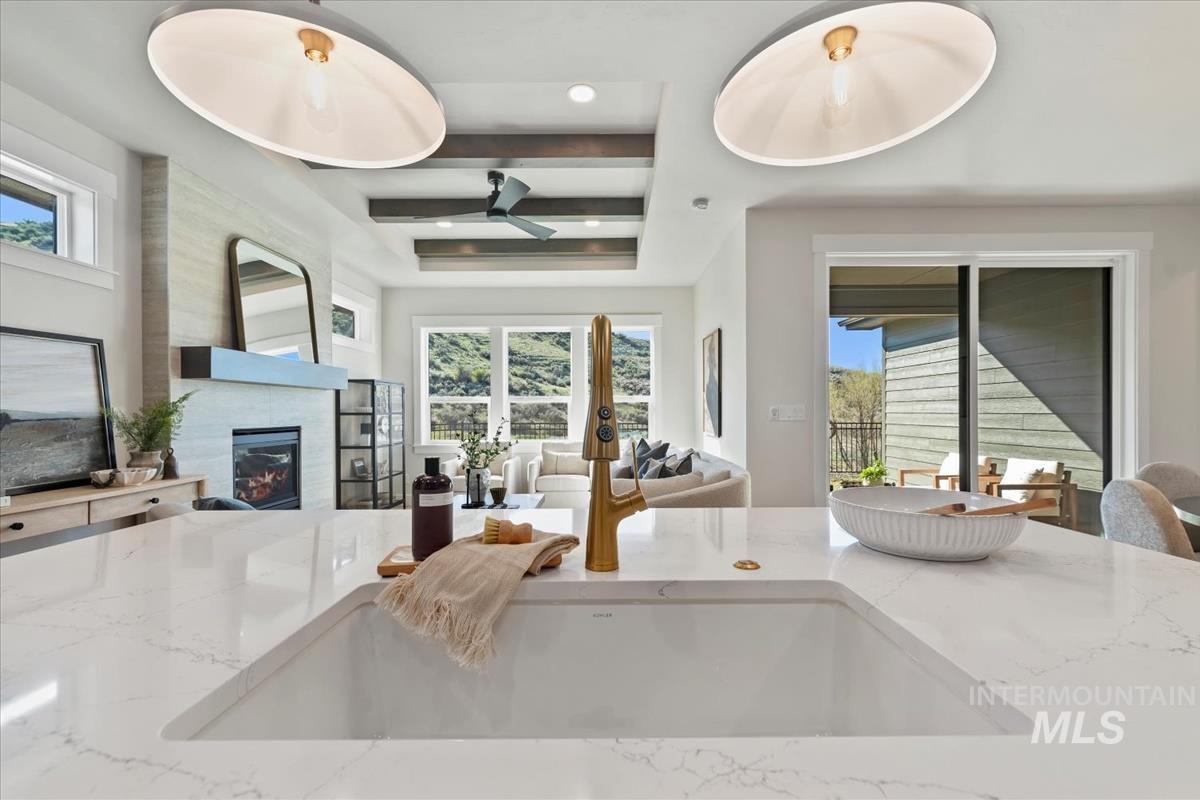 Kitchen featuring light stone counters, open floor plan, a tiled fireplace, a ceiling fan, and recessed lighting