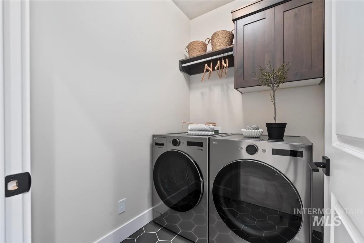 Washroom featuring washer and clothes dryer, cabinet space, and tile patterned floors
