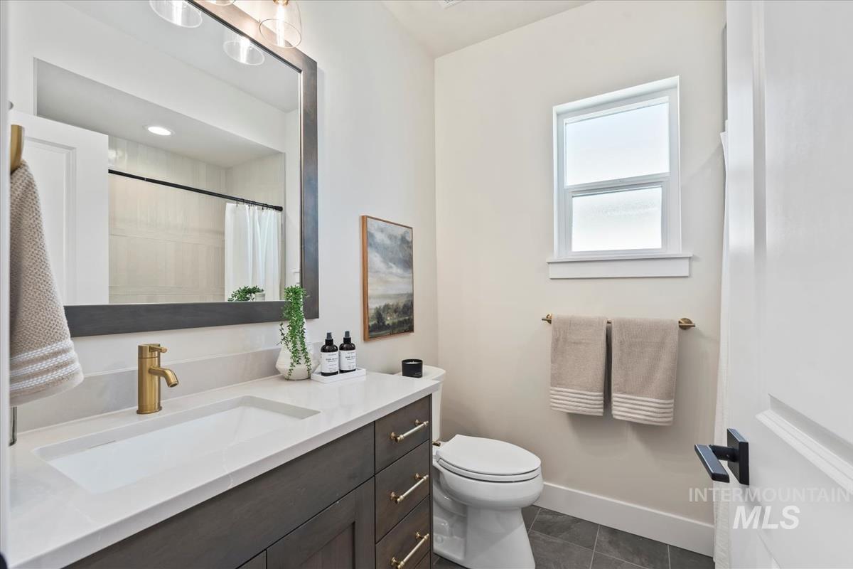 Full bath featuring vanity, curtained shower, and dark tile patterned floors