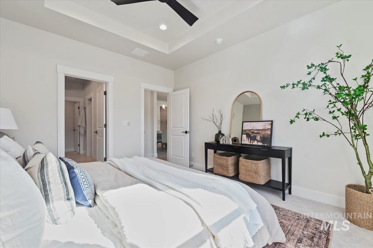 Carpeted bedroom featuring a tray ceiling, ceiling fan, and recessed lighting
