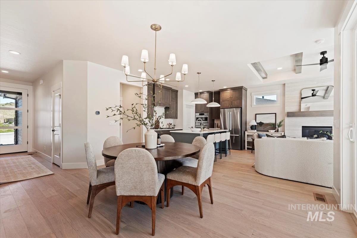 Dining area featuring light wood finished floors, healthy amount of natural light, a chandelier, recessed lighting, and a glass covered fireplace
