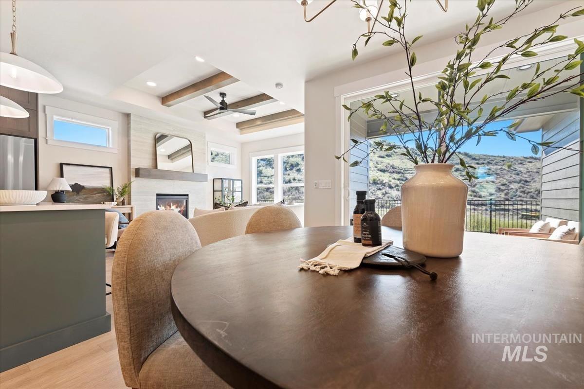 Dining area with beam ceiling, a glass covered fireplace, light wood-style floors, recessed lighting, and a ceiling fan