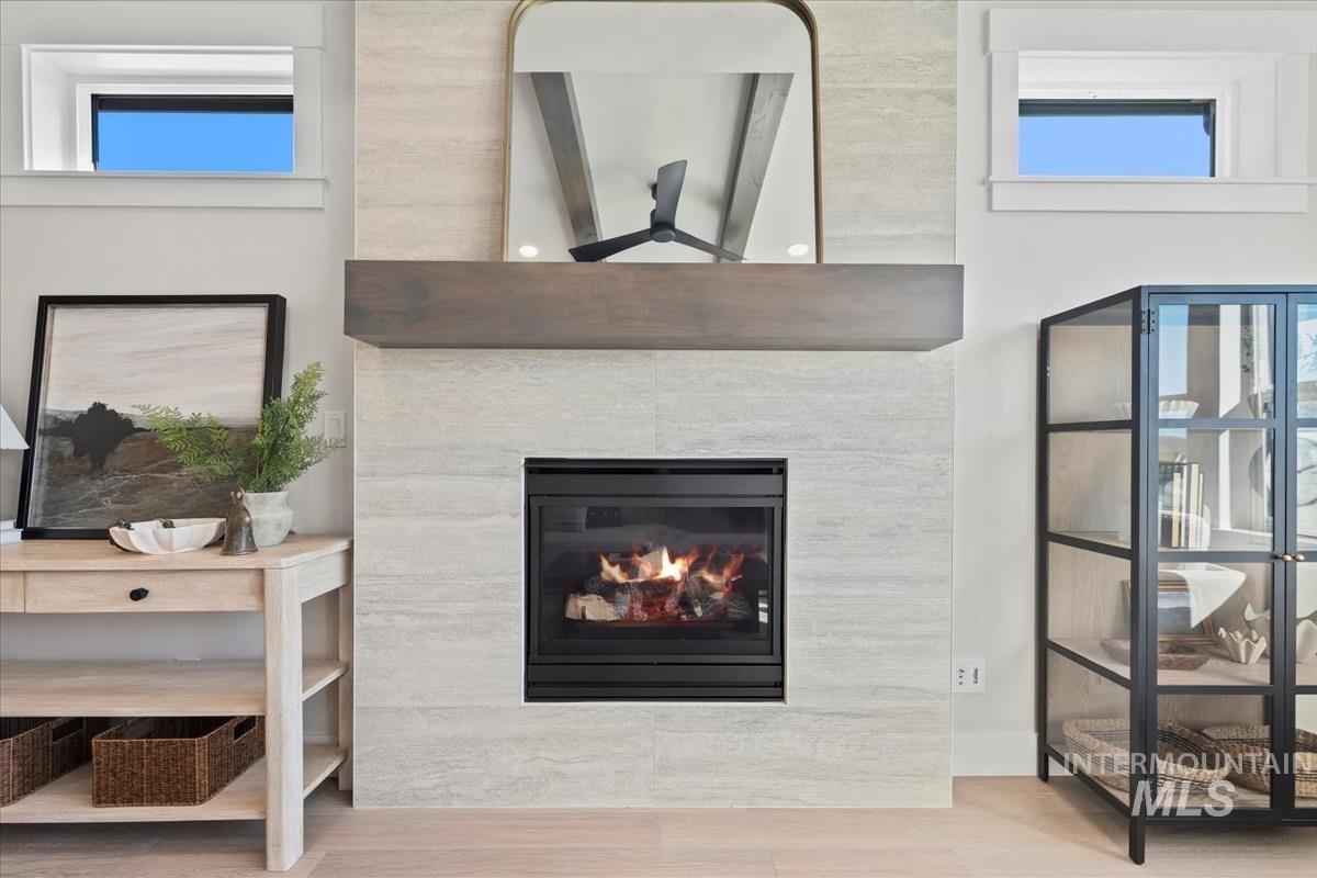 Detailed view of wood finished floors, a glass covered fireplace, and ceiling fan