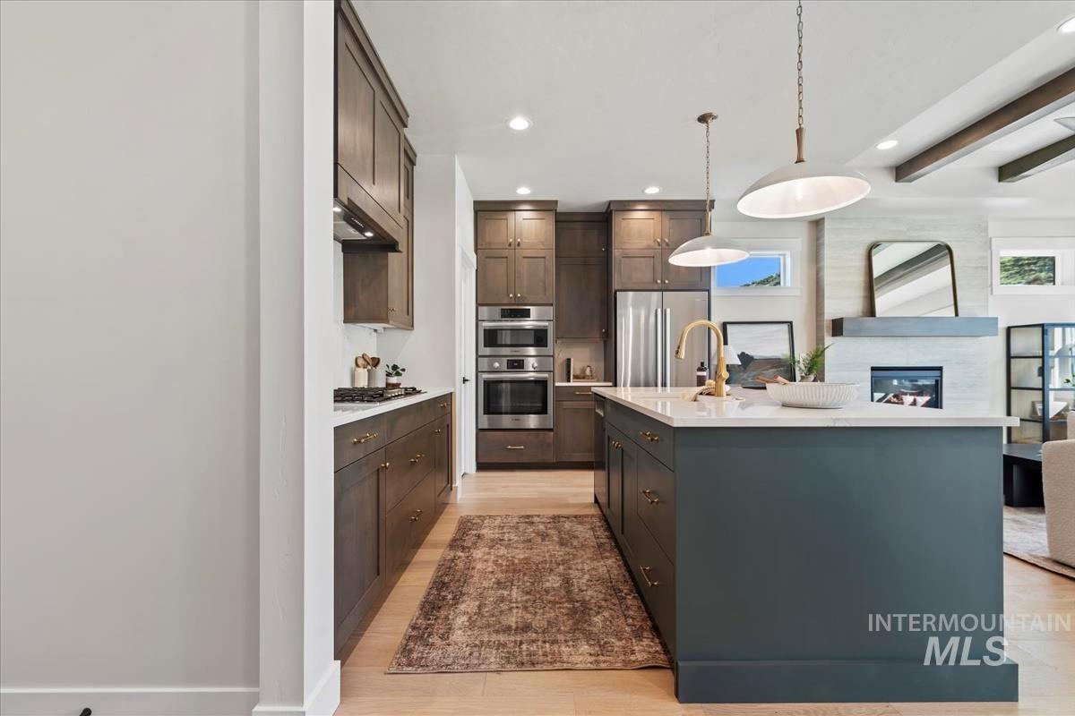 Kitchen with beamed ceiling, pendant lighting, recessed lighting, stainless steel appliances, and open floor plan